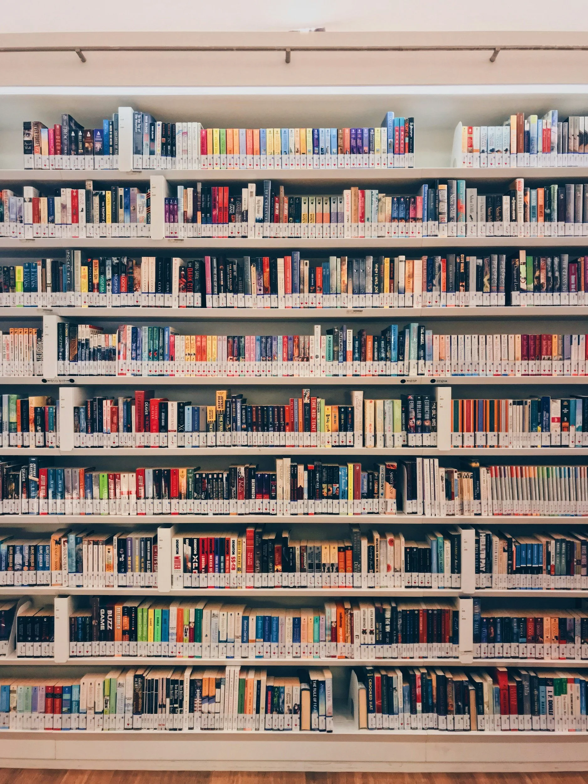 Wide view of a library bookshelf filled with colorful books arranged in rows.