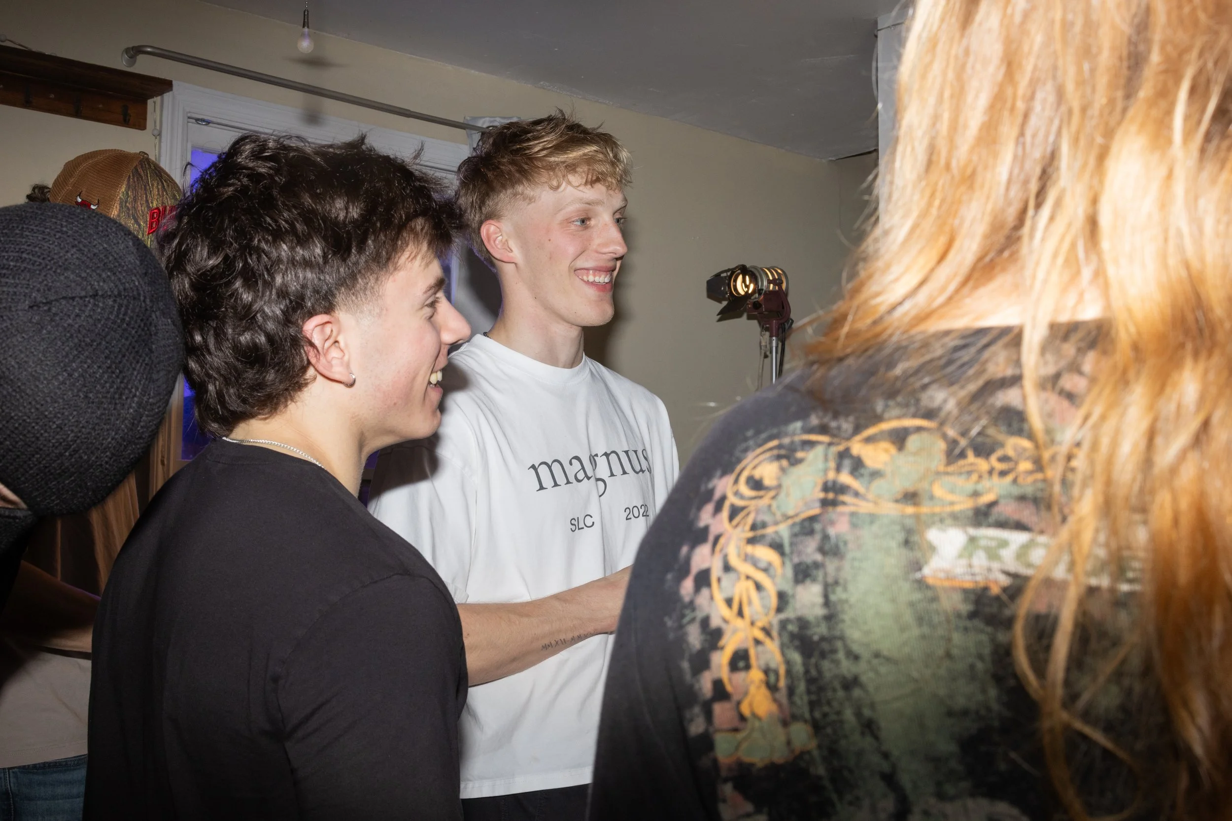 Group of smiling young people talking indoors, with studio lighting and a window in the background.