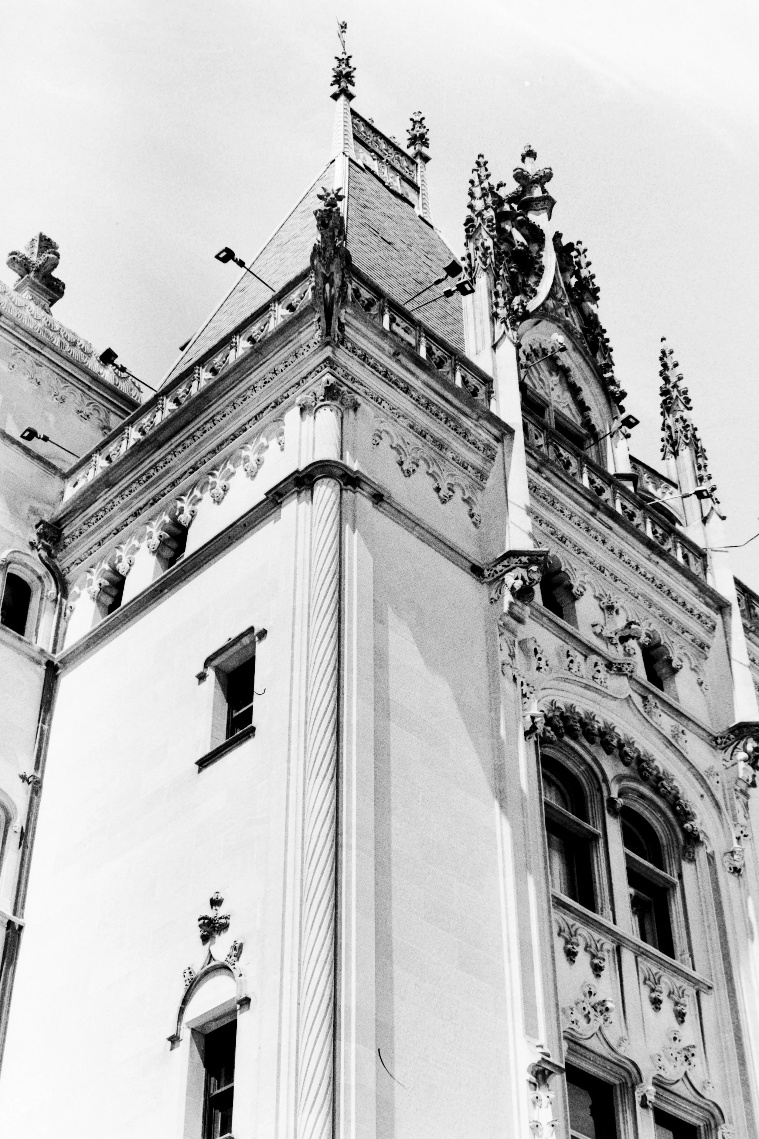 Black and white photograph of a historic ornate castle-like building with elaborate decorative details and pointed architectural features on the upper part.