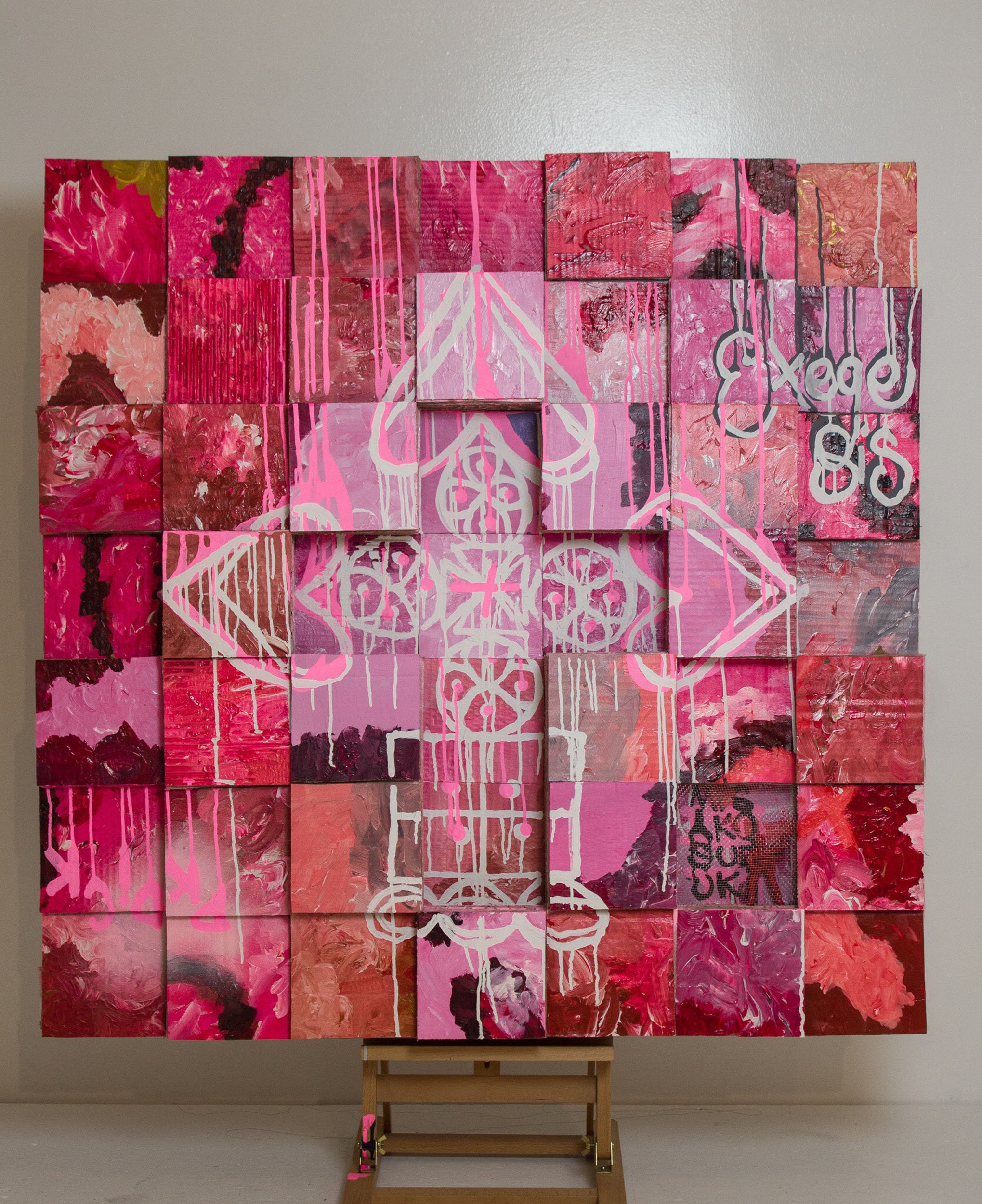 A large grid using cardboard painted squares, featuring various shades of pink and red with white graffiti-style Ethiopian crucifix design in the center and the word "EXEGESIS" and "PKDICK" on the upper right/lower left