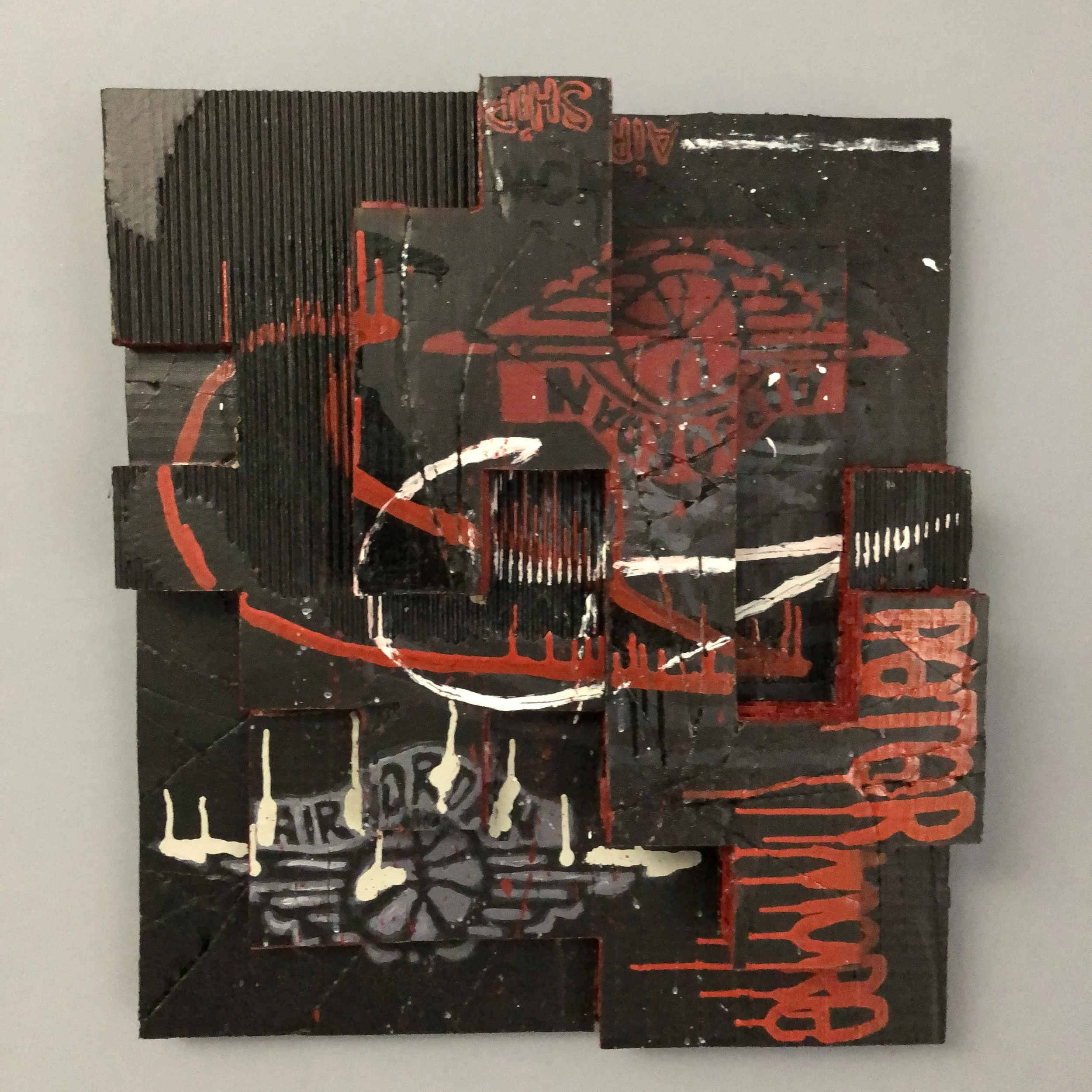 A mixed-media art piece using cardboard divided into various shapes at differing heights to give the illusion of depth. Black background with red and white markingS and "AIR JORDAN" logo's. The name of a Nike designer "PETER" lower right in red ink.