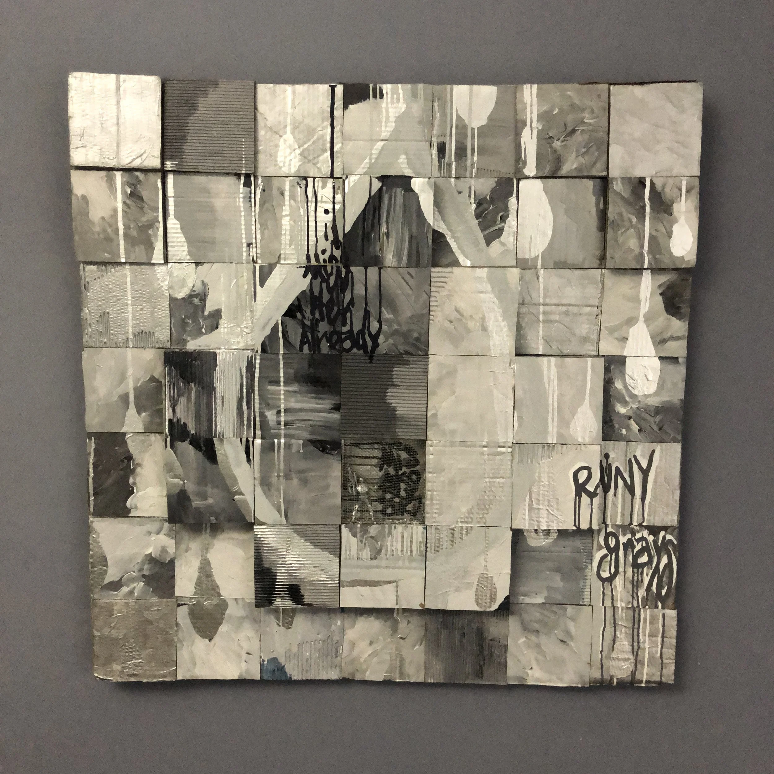 Mixed media art piece composed of small square tiles in grayscale, arranged to form a composite image with abstract and text elements, including graffiti-style writing that says 'RUNY' and other partially obscured words.