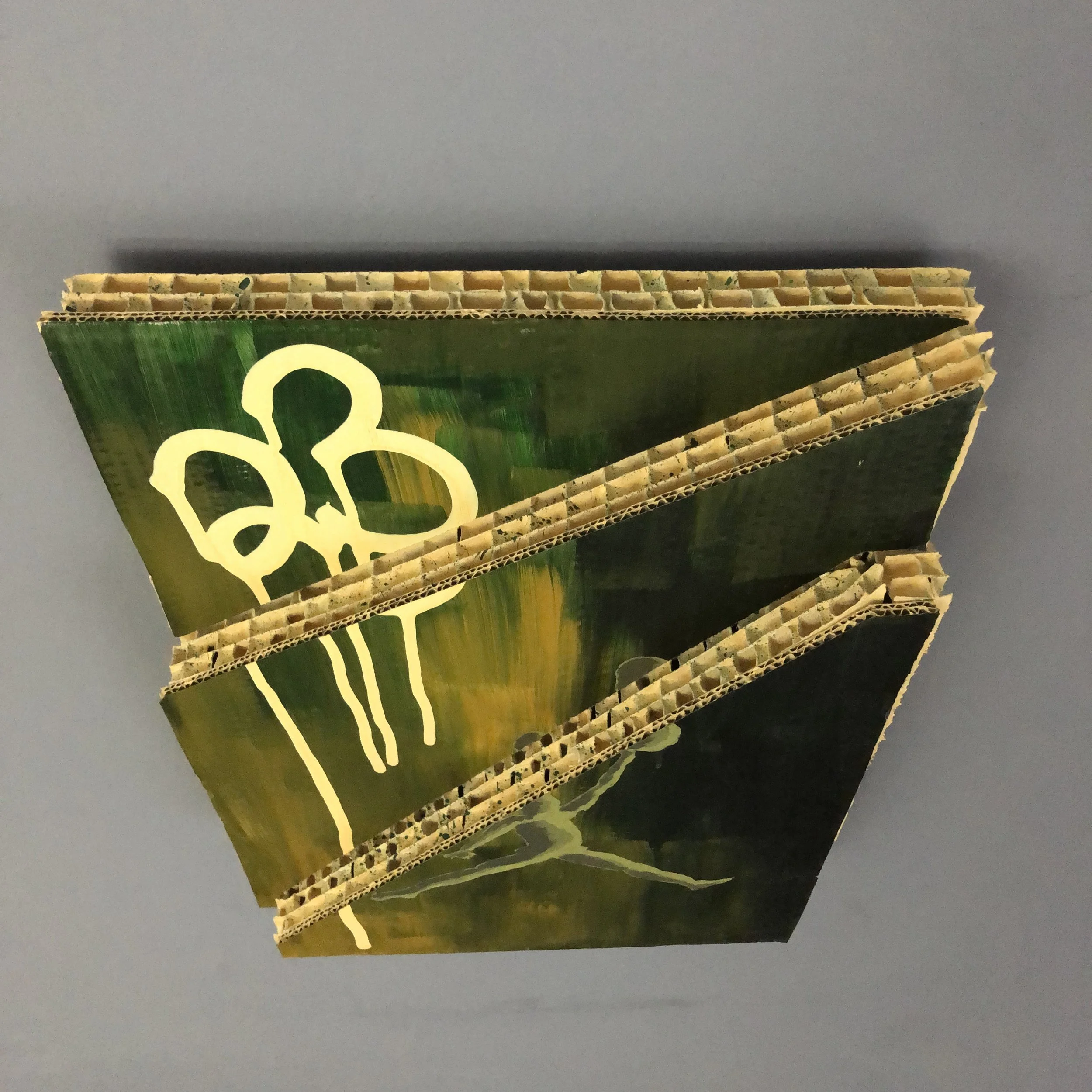 A mixed-media art piece composed of cardboard arranged in an abstract design, divided into 3 pieces at differing heights, with a yellow "23" in ink and a "AIR JORDAN" logo in the lower half pained in a pea green tint.