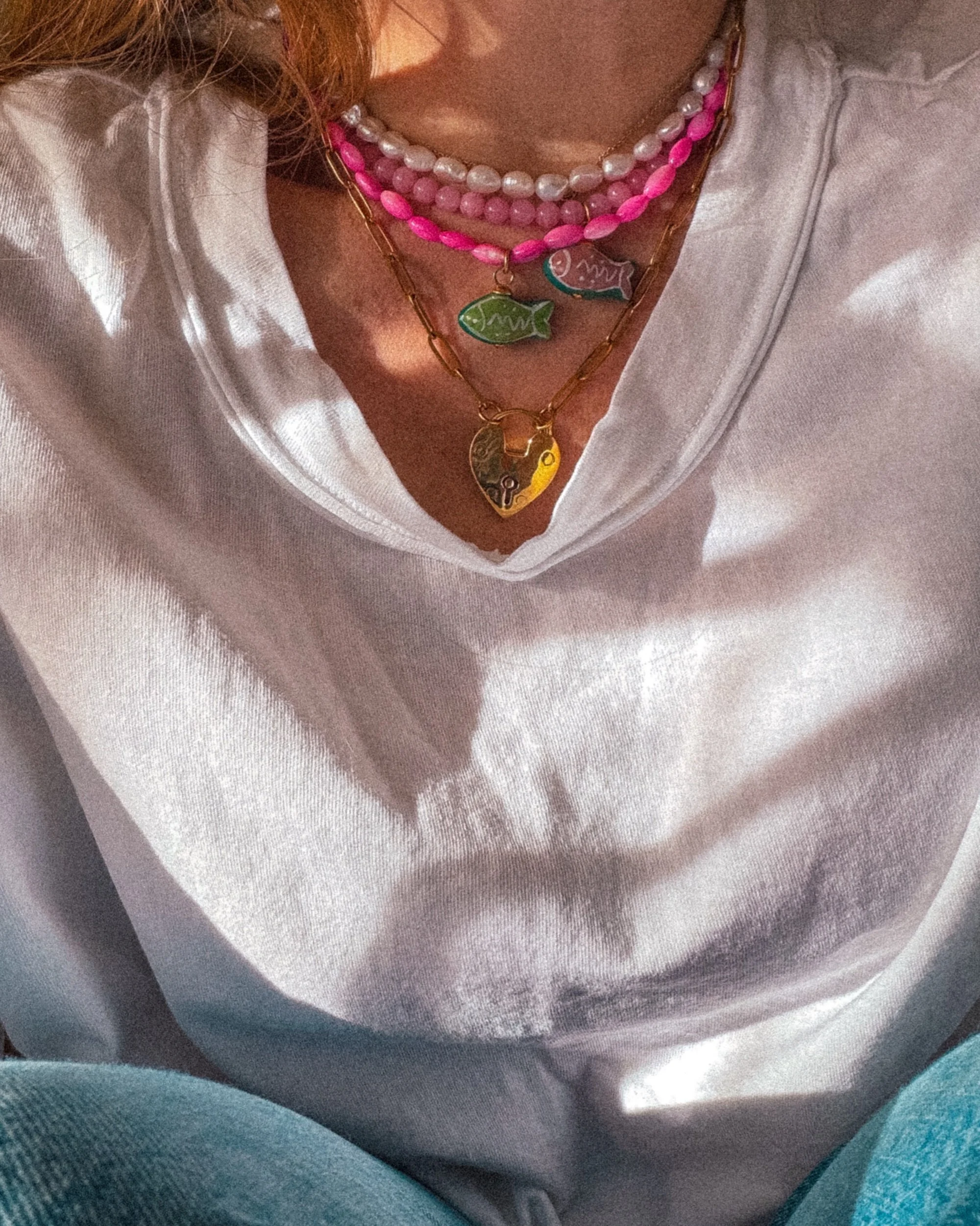 necklace stack featuring beaded necklaces and gold heart lock necklace