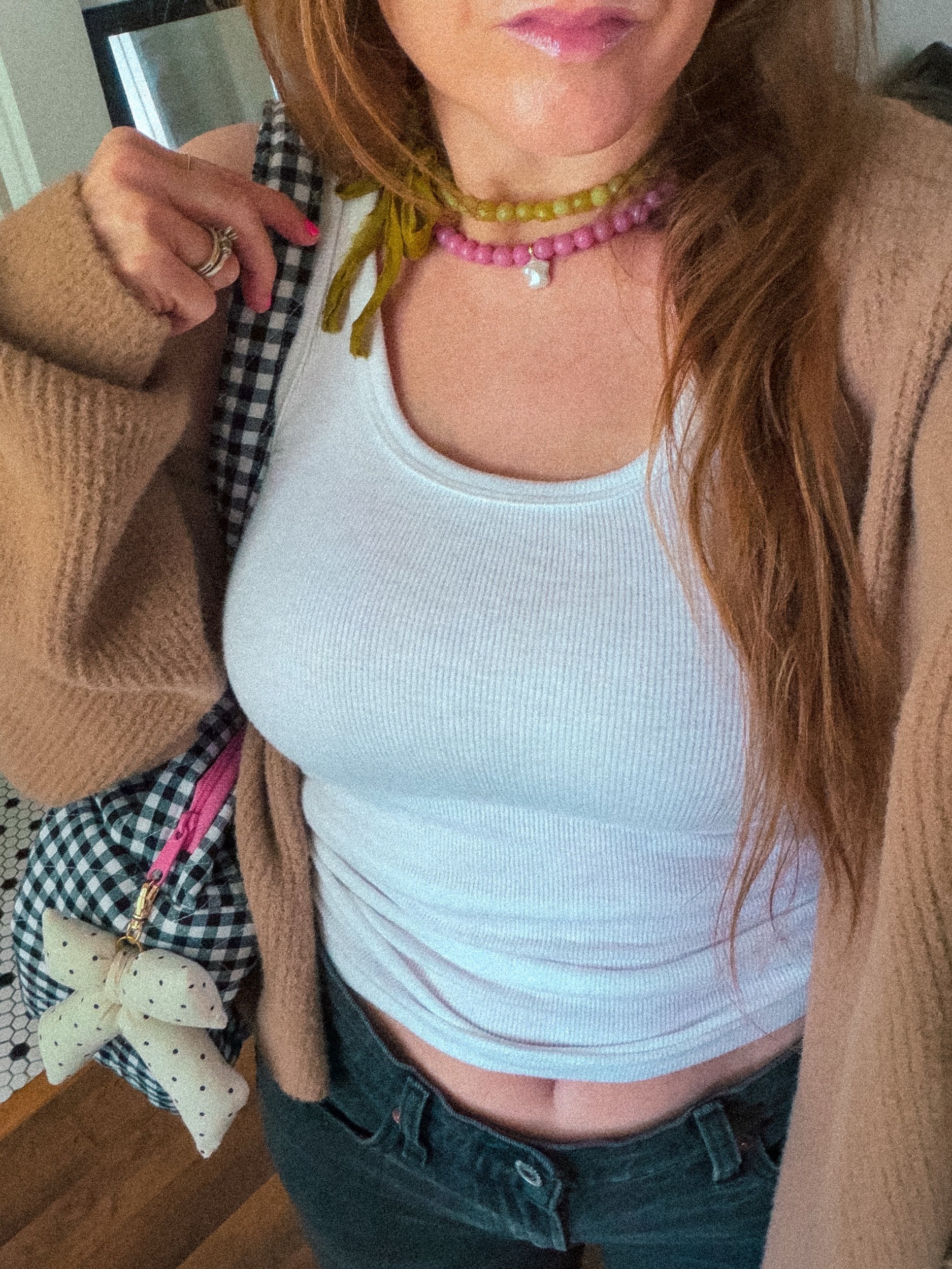 Handmade polka dot bow bag charm on a gingham bag, worn with a white ribbed tank top and brown cardigan