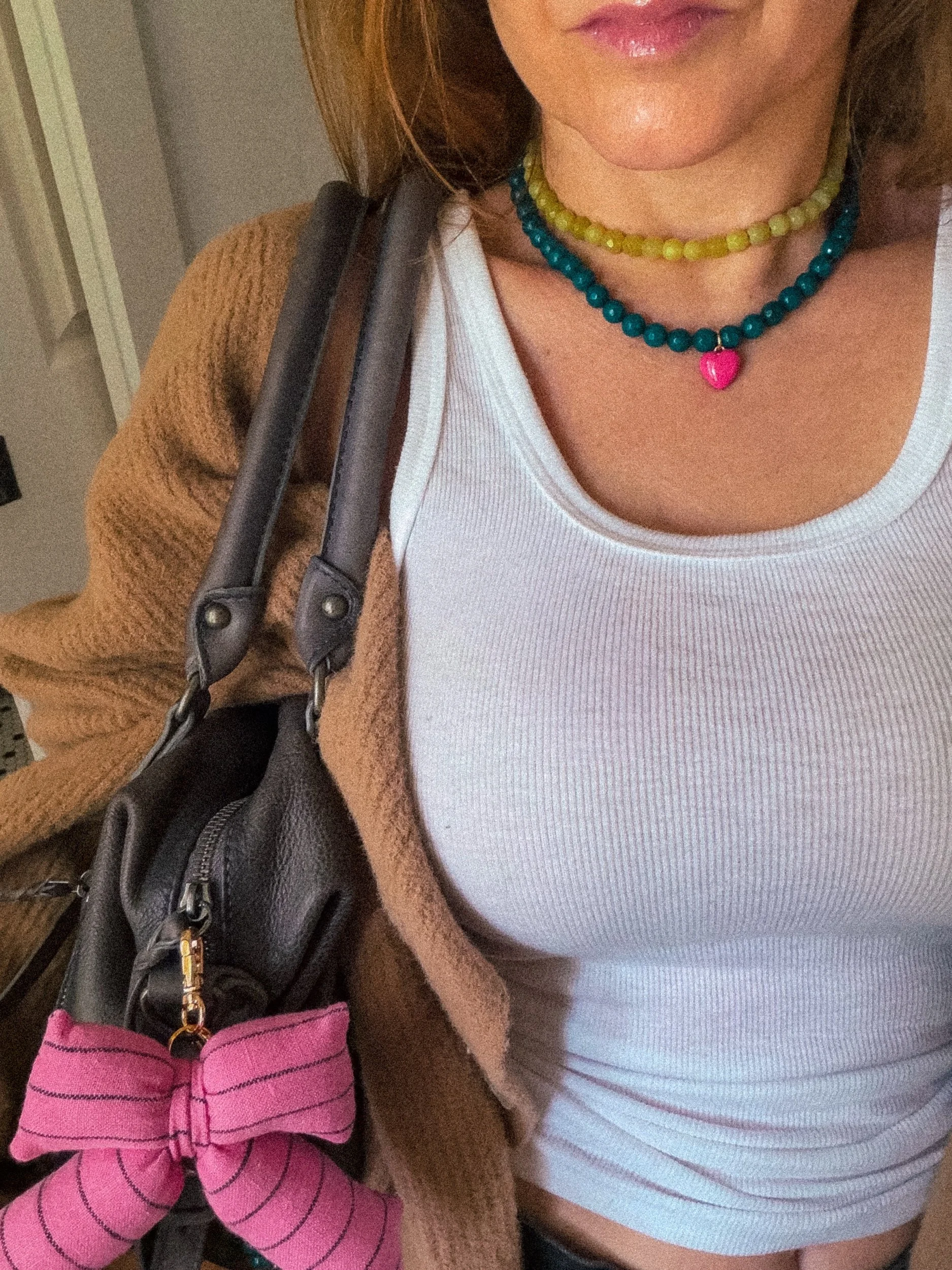 Chartreuse beaded necklace layered with a teal beaded necklace with pink heart charm, worn with a white ribbed tank top and brown cardigan