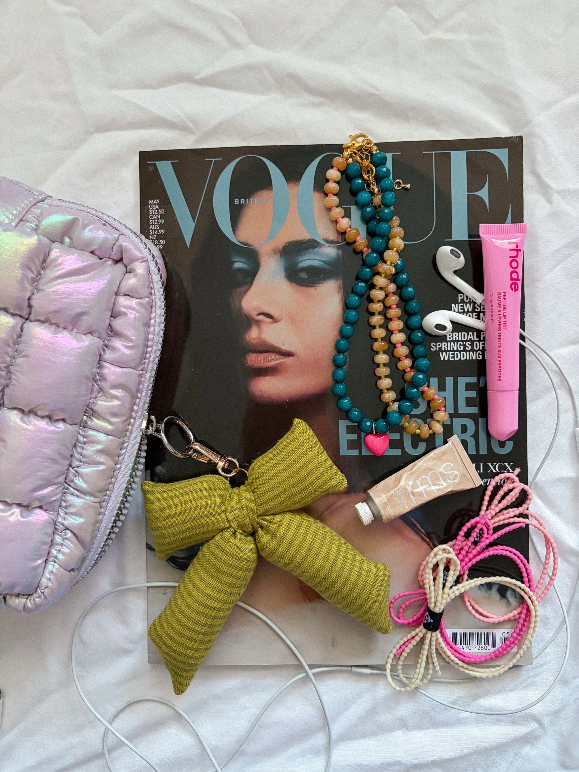 Handmade chartreuse striped bow bag charm in a flat lay with a lavender puffer pouch and teal and amber beaded charms