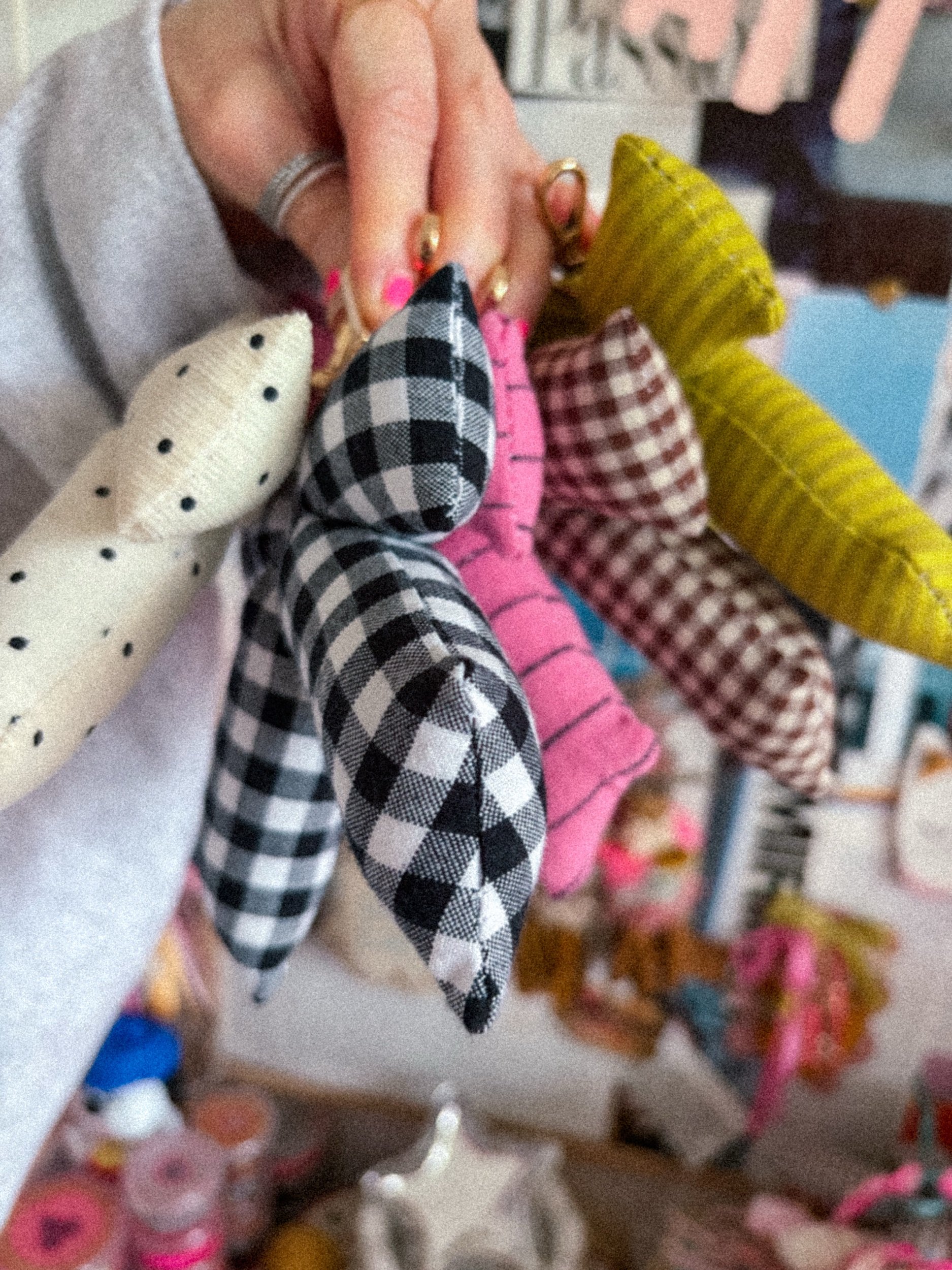 Collection of puffy bow bag charms in chartreuse stripe, gingham, polka dot, and pink held in one hand