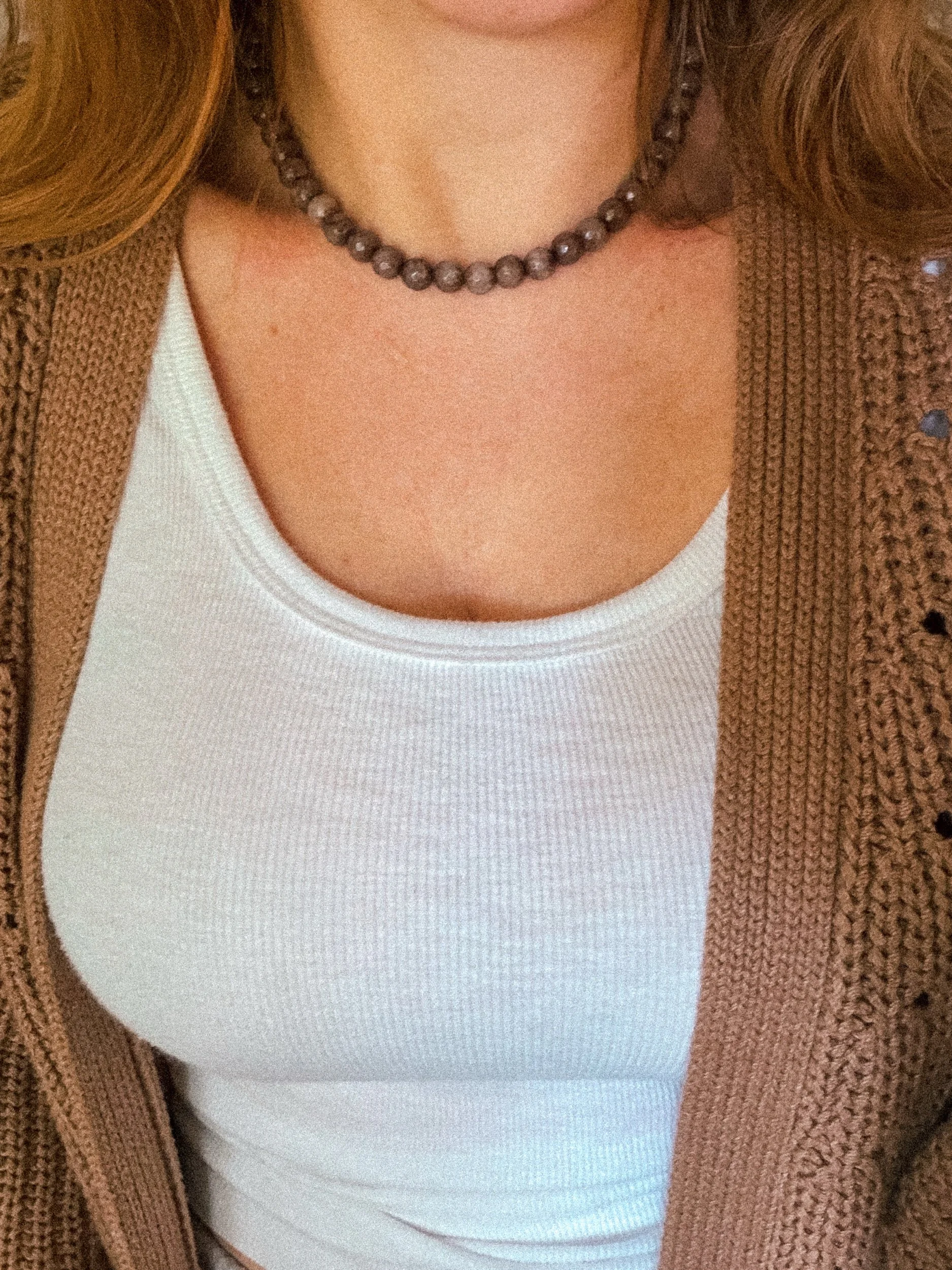 Brown beaded necklace worn with a white ribbed tank top and brown knit cardigan