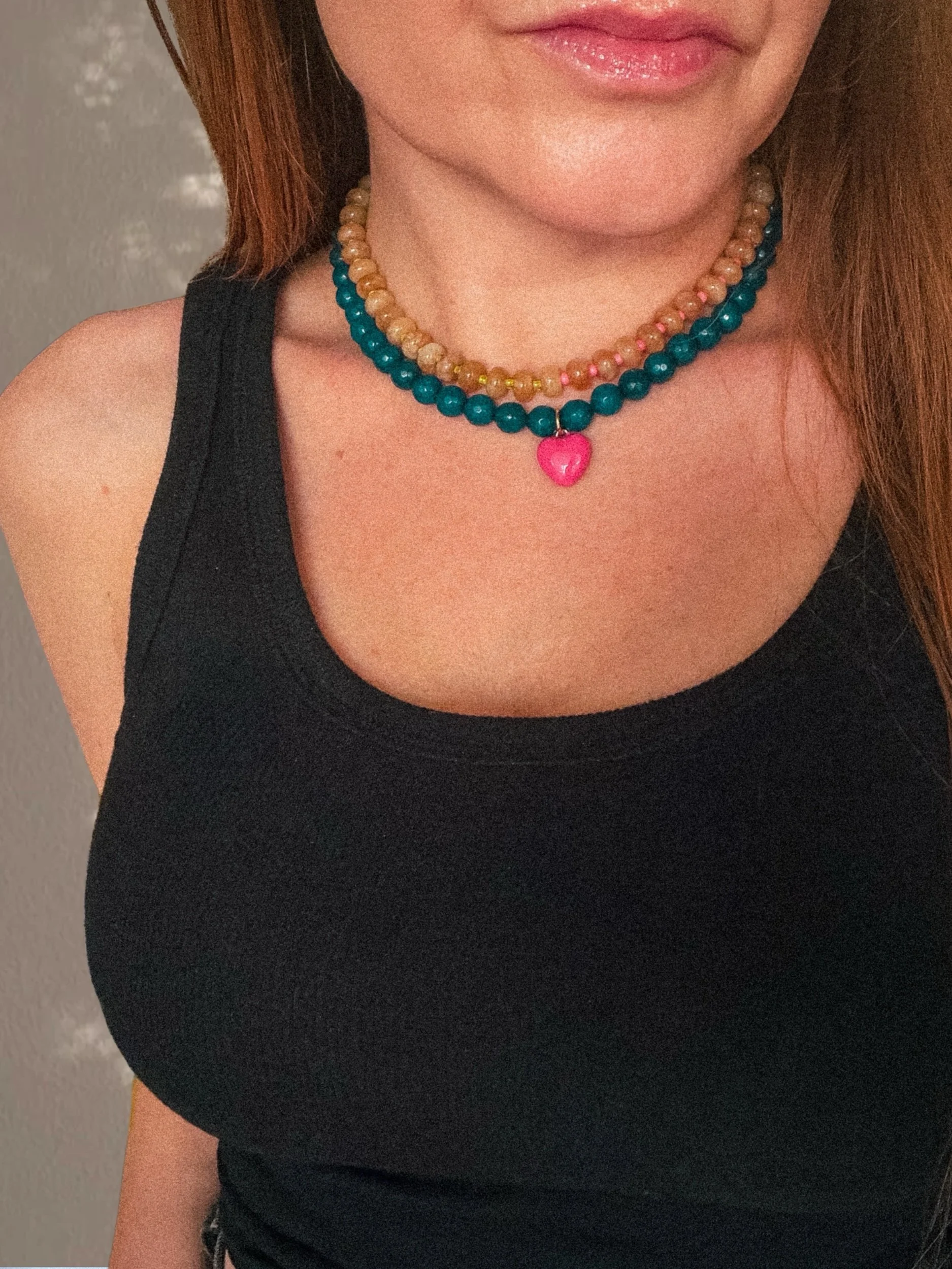 Golden Hour Tan Beaded Necklace layered with a teal beaded necklace with pink heart charm, worn with a black tank top