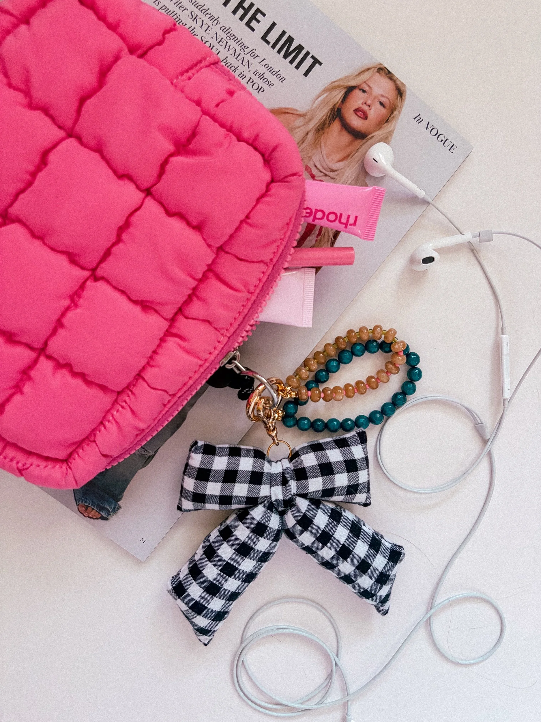 Handmade gingham bow bag charm in a flat lay with a teal and amber beaded bag charm and a quilted pink pouch