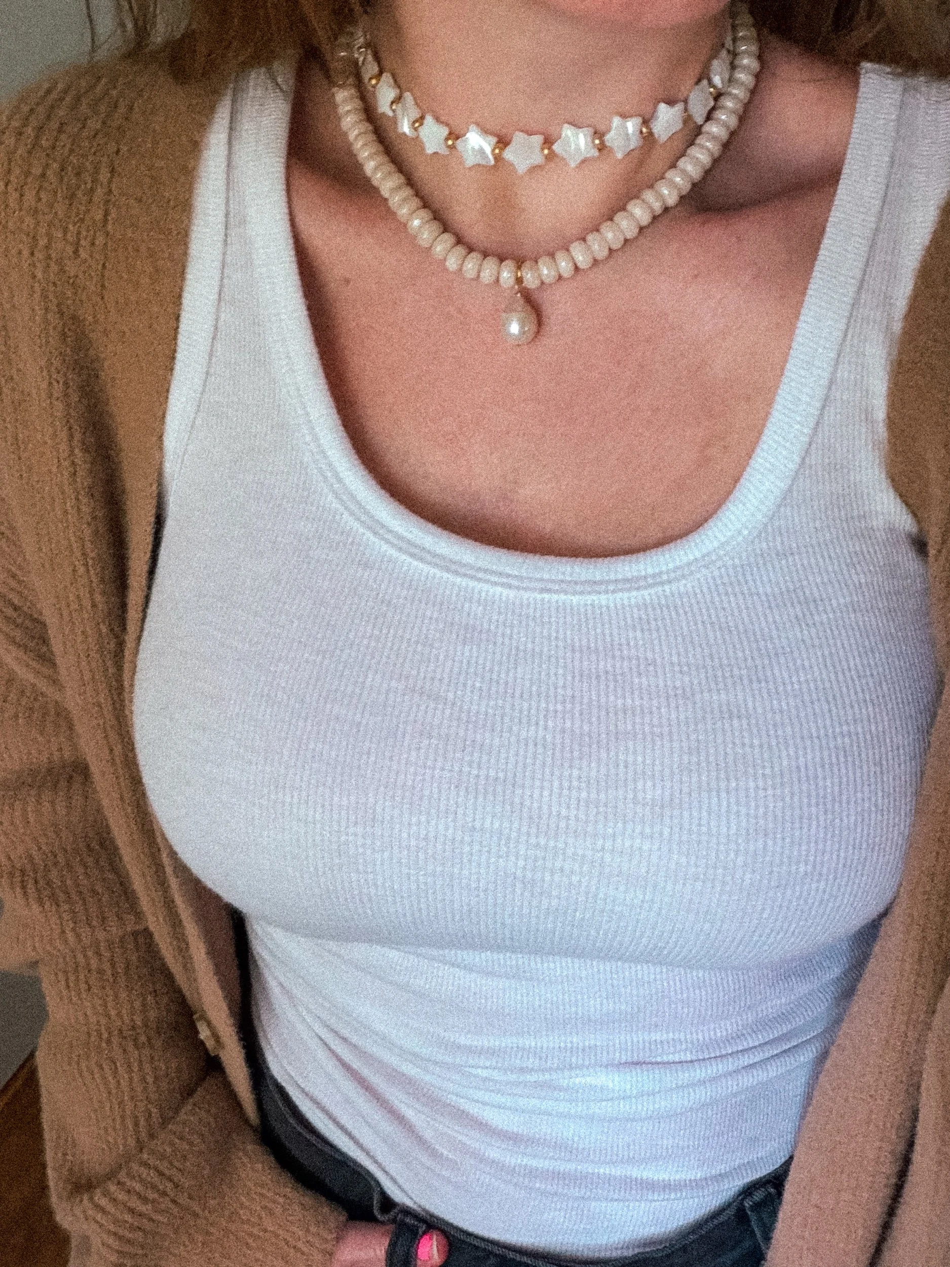 Cream beaded necklace with pearl drop charm worn with a white ribbed tank top and brown cardigan