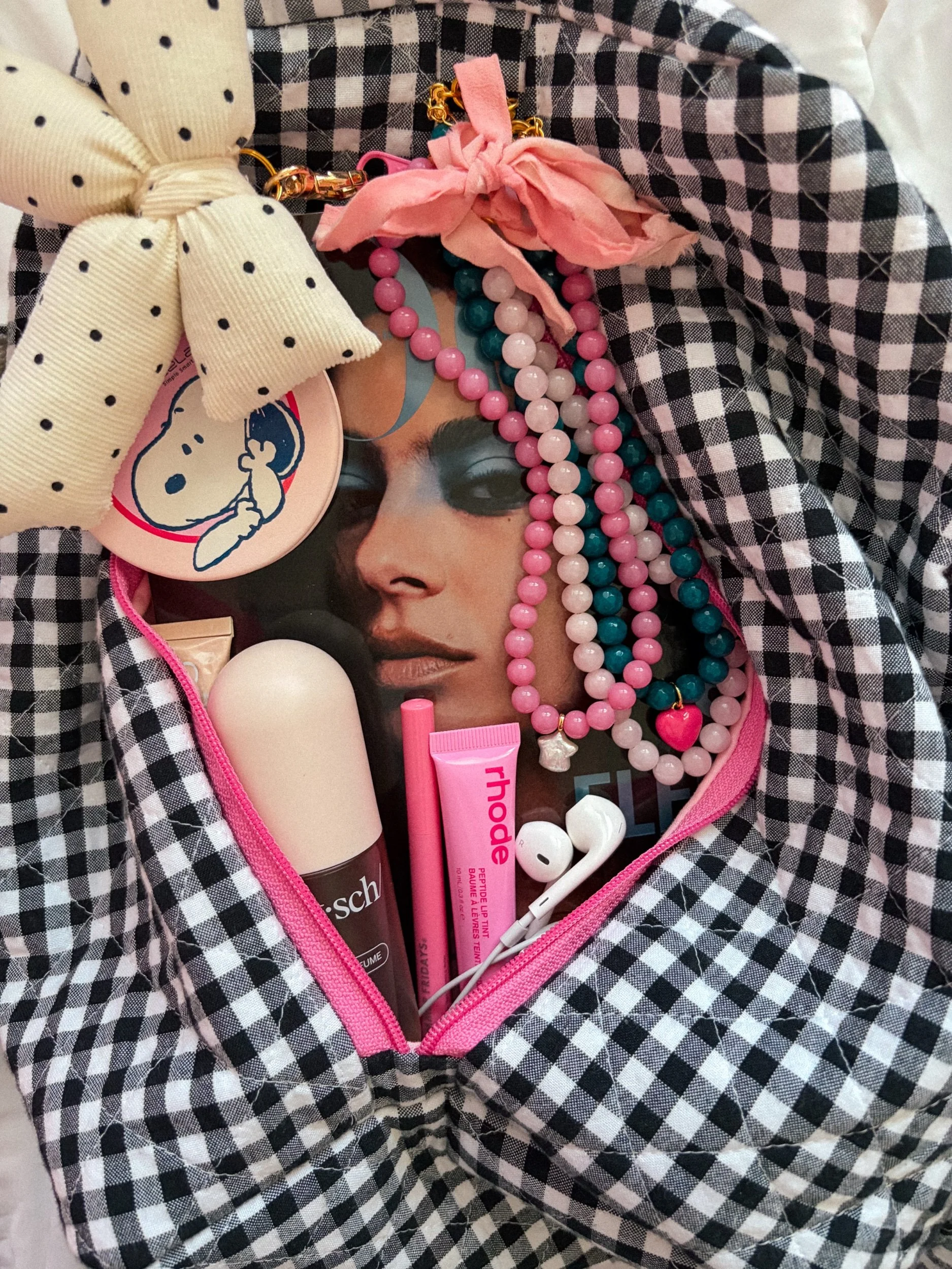 Handmade blush beaded necklace with pink bow styled with other beaded necklaces in a black and white gingham bag