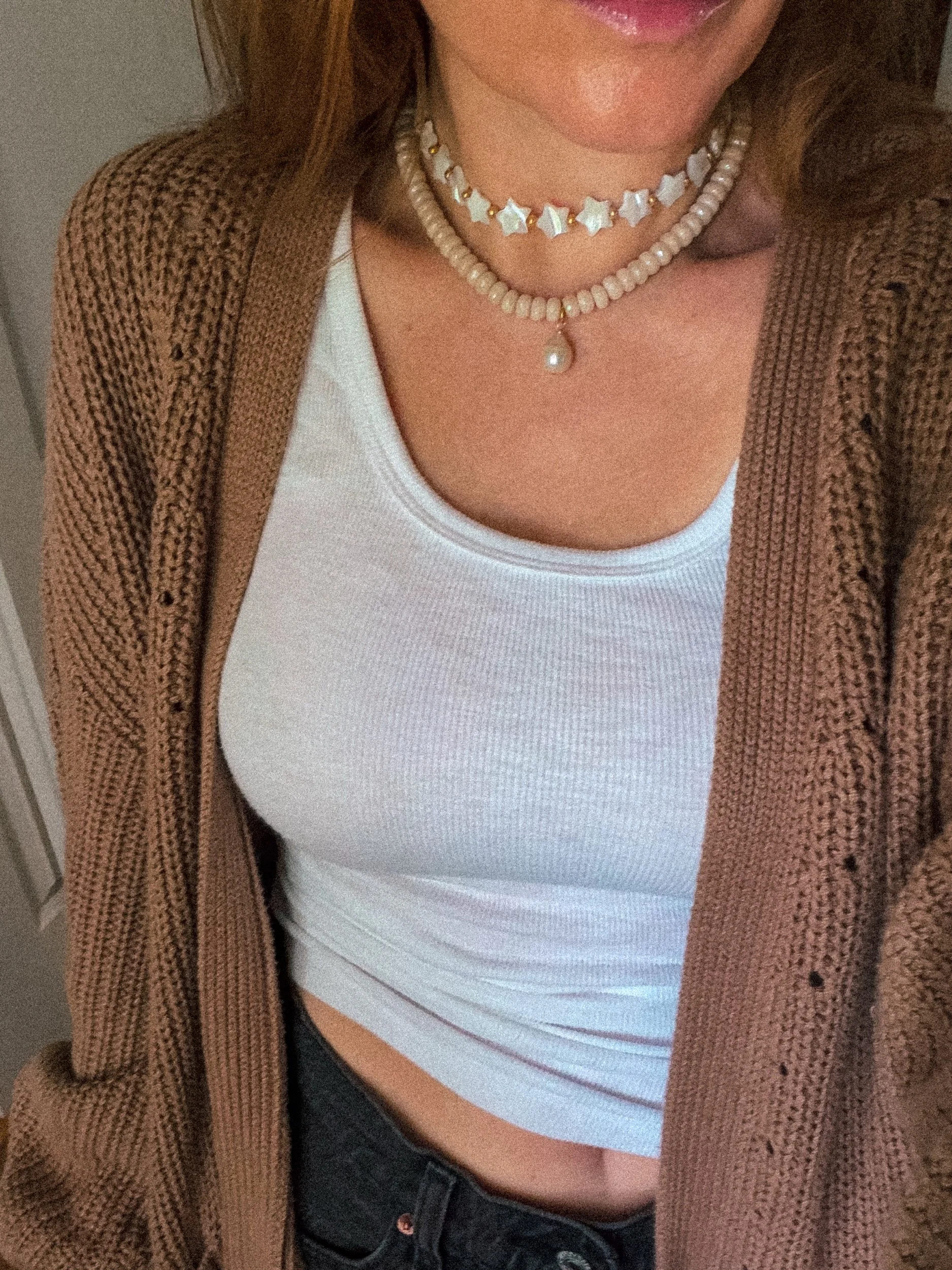 Star bead choker layered with a pink beaded necklace, worn with a white tank top and brown knit cardigan