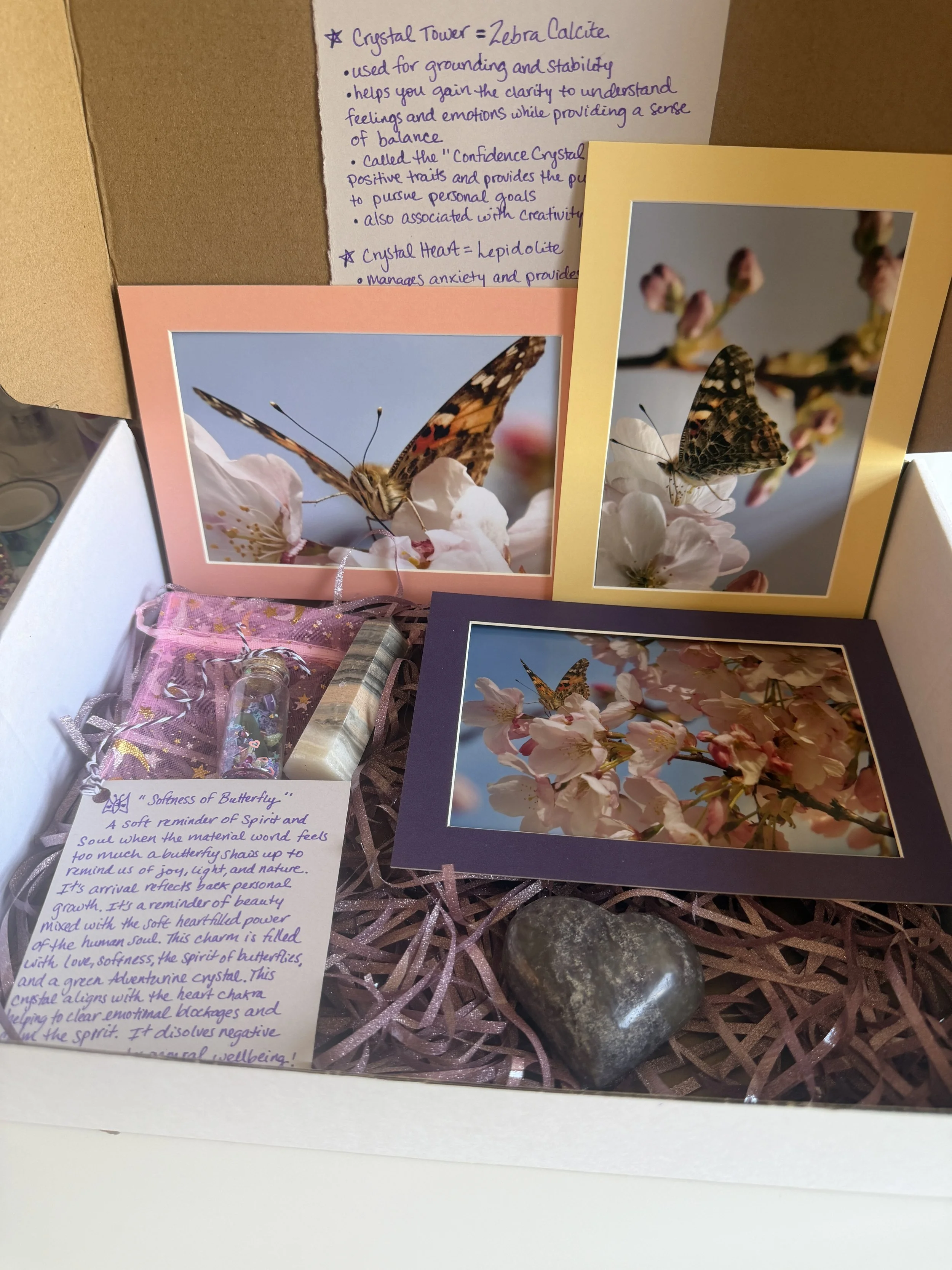 Note with information about a crystal tower, crystal heart, and the qualities they symbolize, accompanied by photographs of butterflies on flowers, surrounded by decorative pink ribbons, stones, and a pink gift bag.
