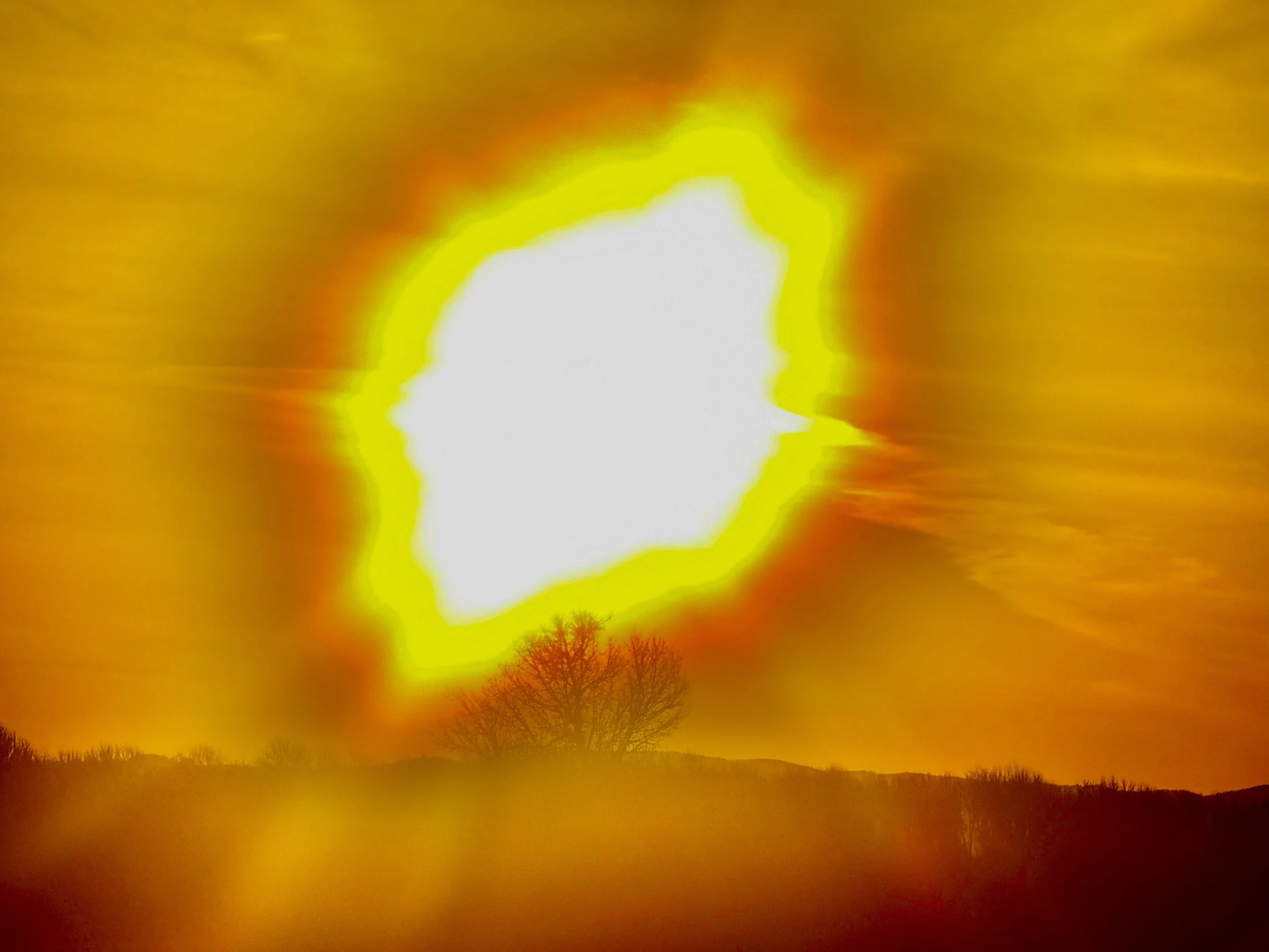 Bright white light surrounded by yellow, orange, and red hues in a sunset or sunrise scene with silhouetted trees and horizon.