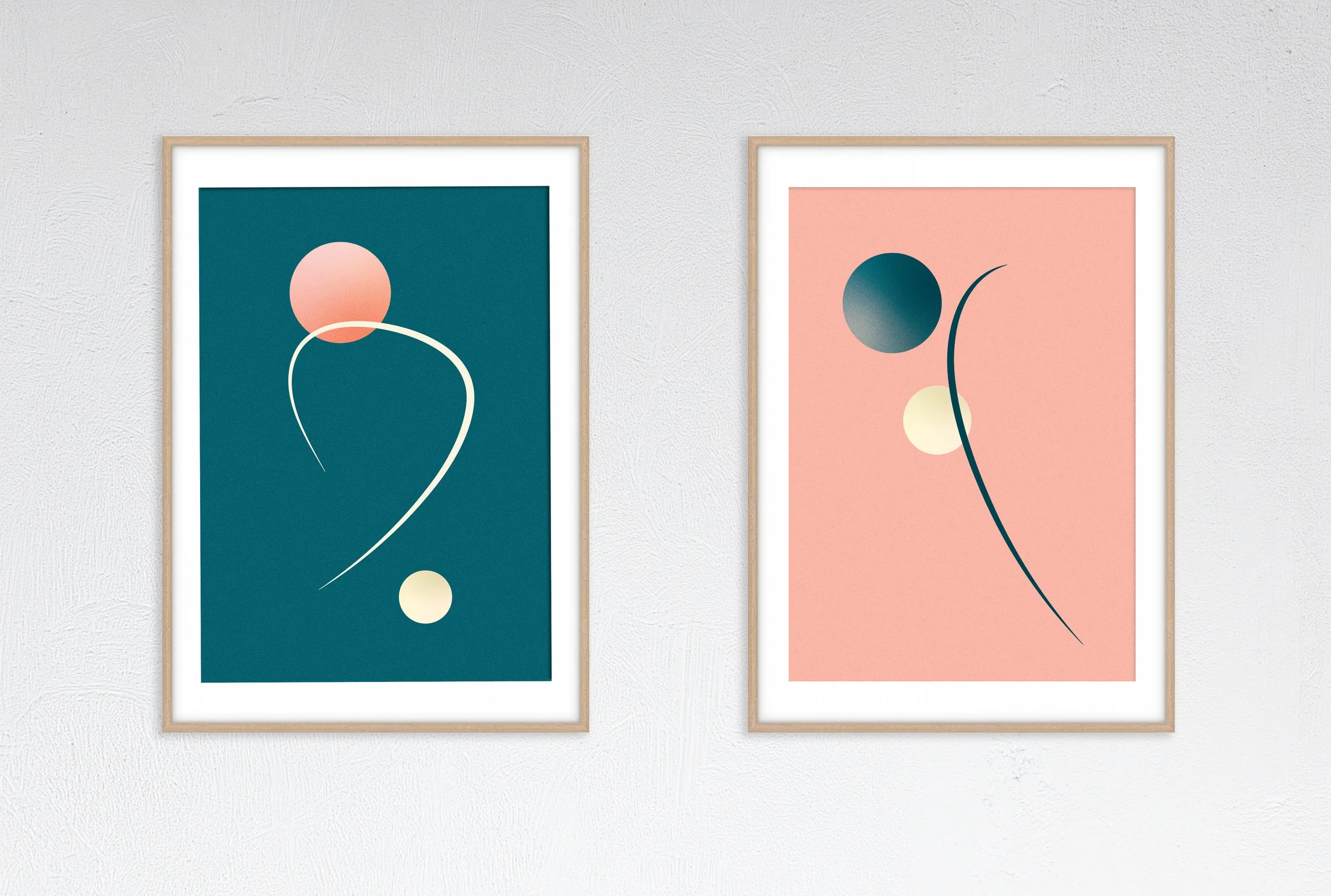Two framed abstract art prints hanging on a white wall, featuring geometric shapes like circles and lines in shades of blue, pink, and yellow.