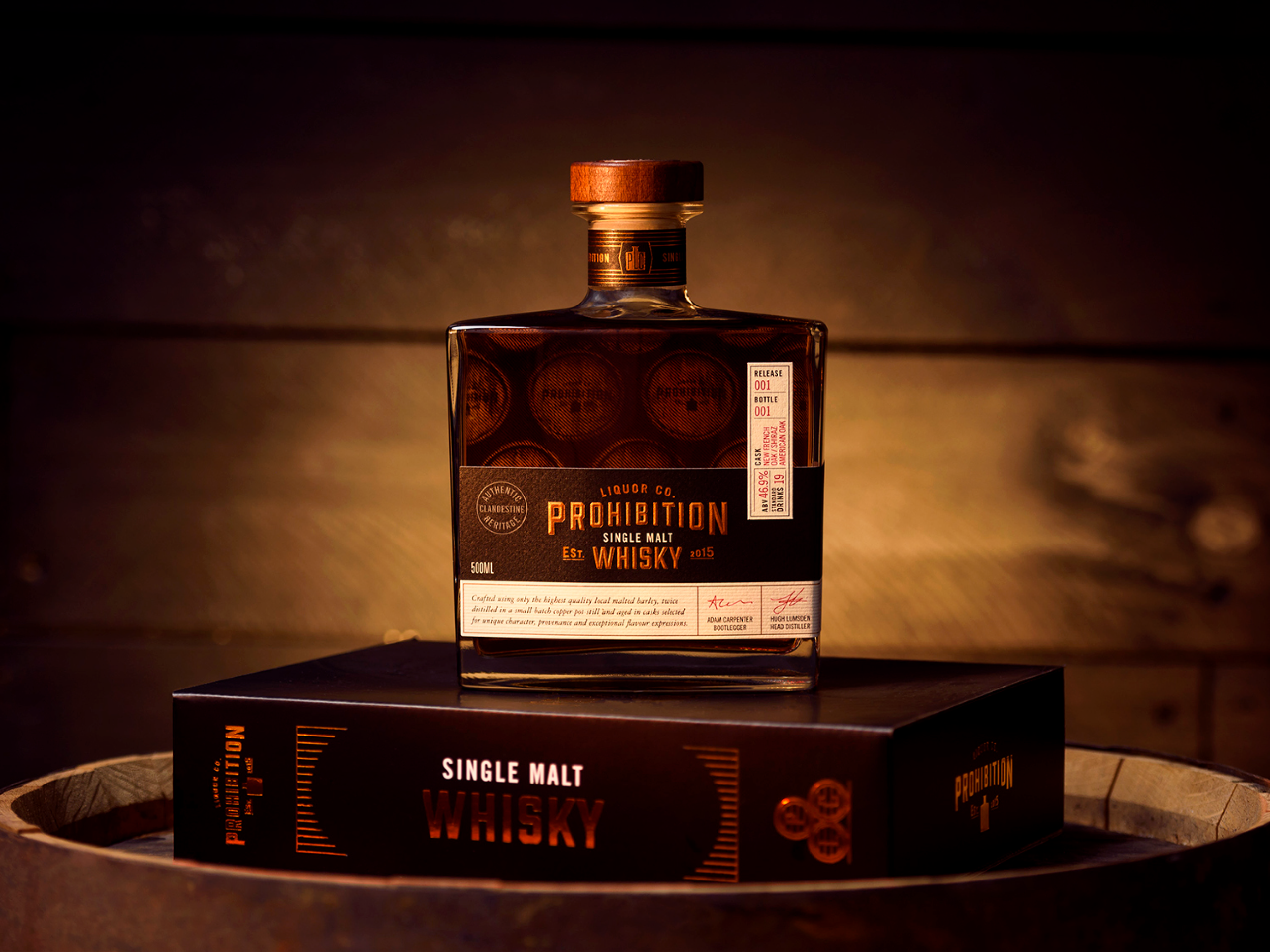 A bottle of whiskey displayed on a platform with a dark background and warm lighting.