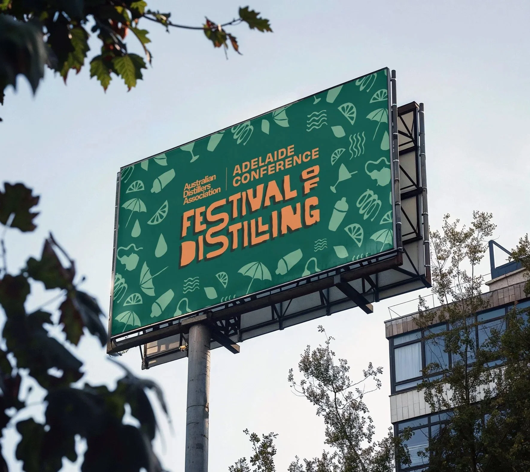 A large outdoor billboard advertising the Adelaide Conference and the Australian Distillers Association, with decorative elements like slices of citrus, umbrellas, and drink glasses in a green background.