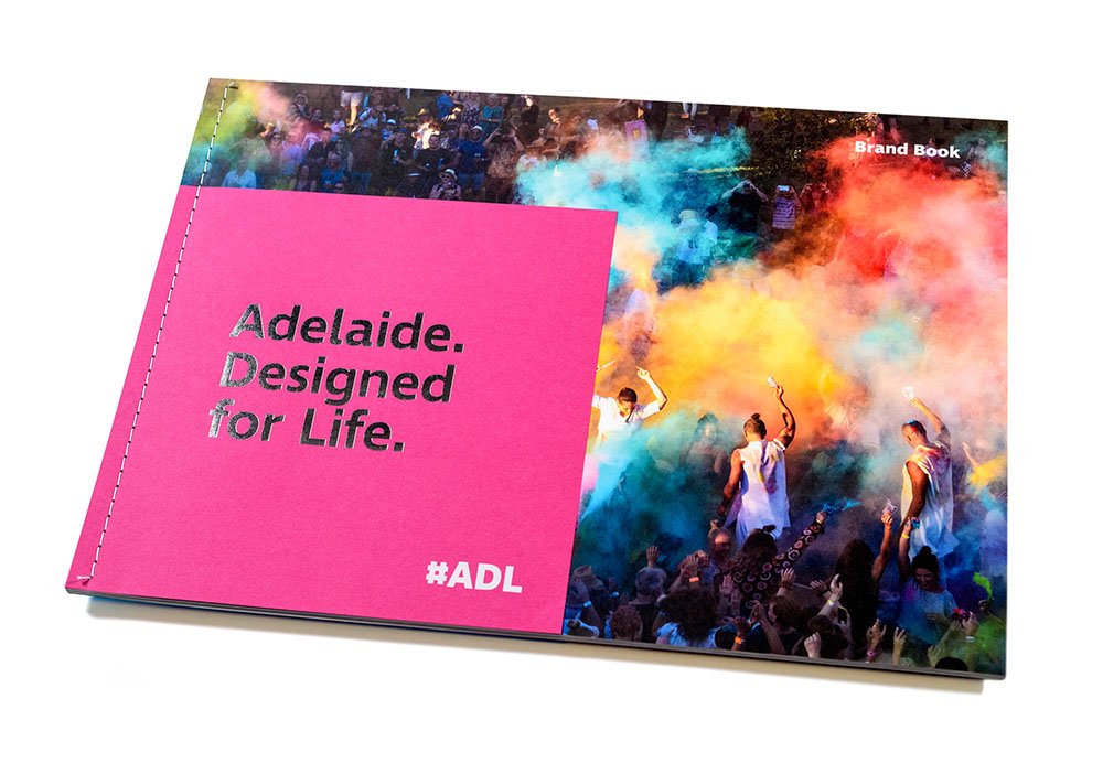 Open brand book with a vibrant photo of a festival with colorful powder and people dancing inside.