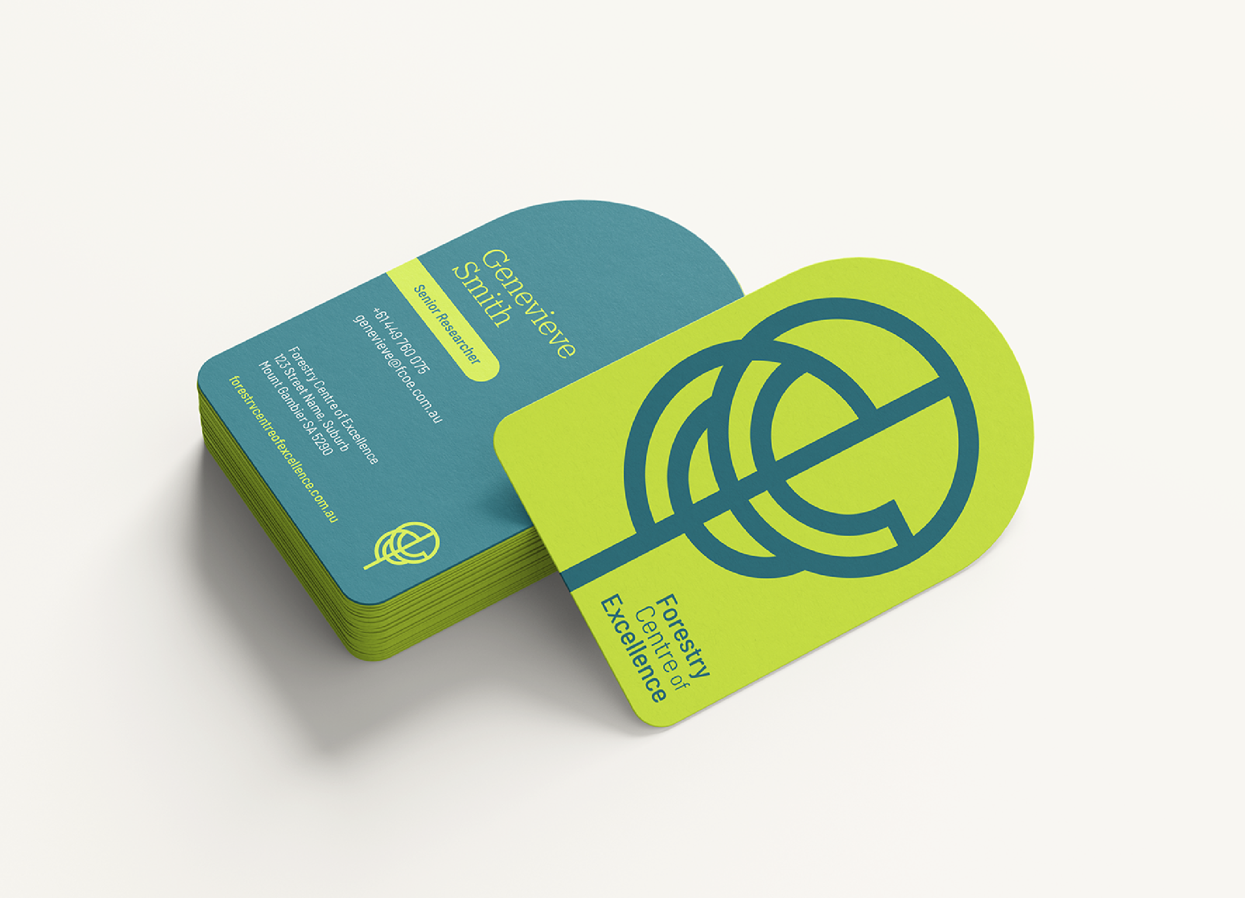 Business cards stacked on a white surface with bright green and blue colors. The card on top has the name 'Genevieve Smith' and title 'Senior Researcher,' along with contact details and the organization 'Forestry Centre of Excellence'.