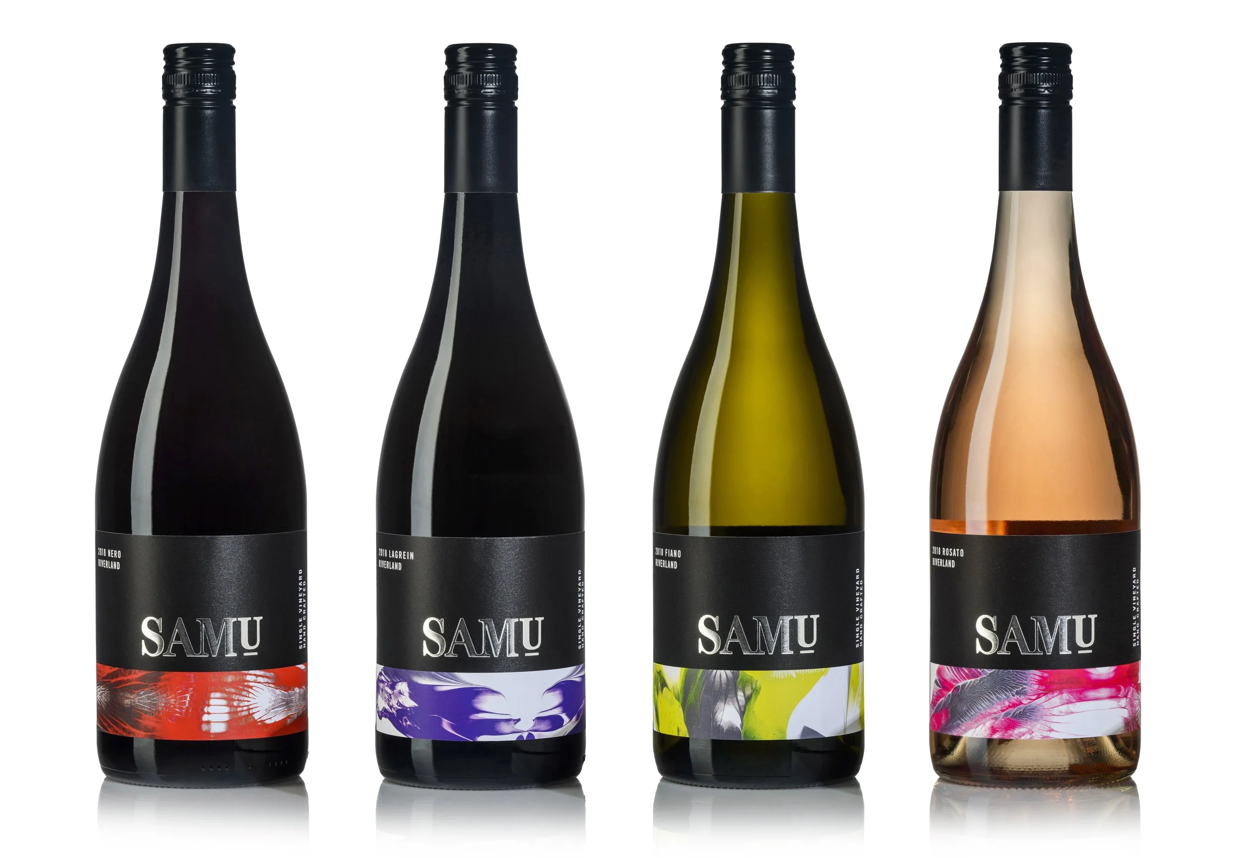 Four bottles of wine with black caps, each featuring a colorful label with abstract floral or botanical designs, lined up against a white background.