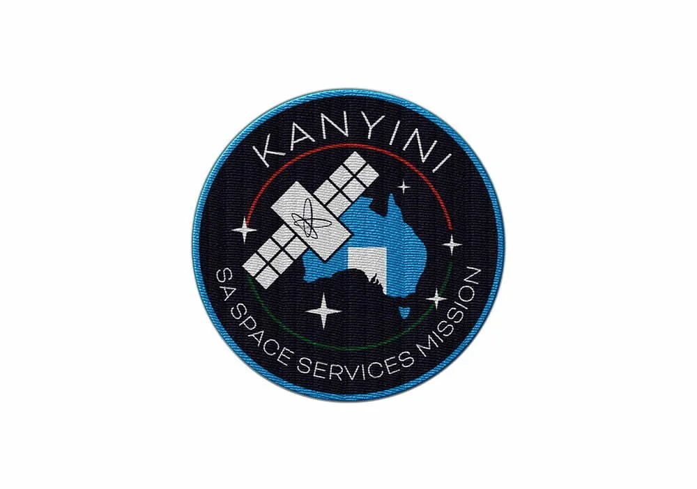 Patch with the NASA Kanyini Space Services Mission logo, featuring a satellite, the outline of Australia, and space elements on a black background with a blue border.