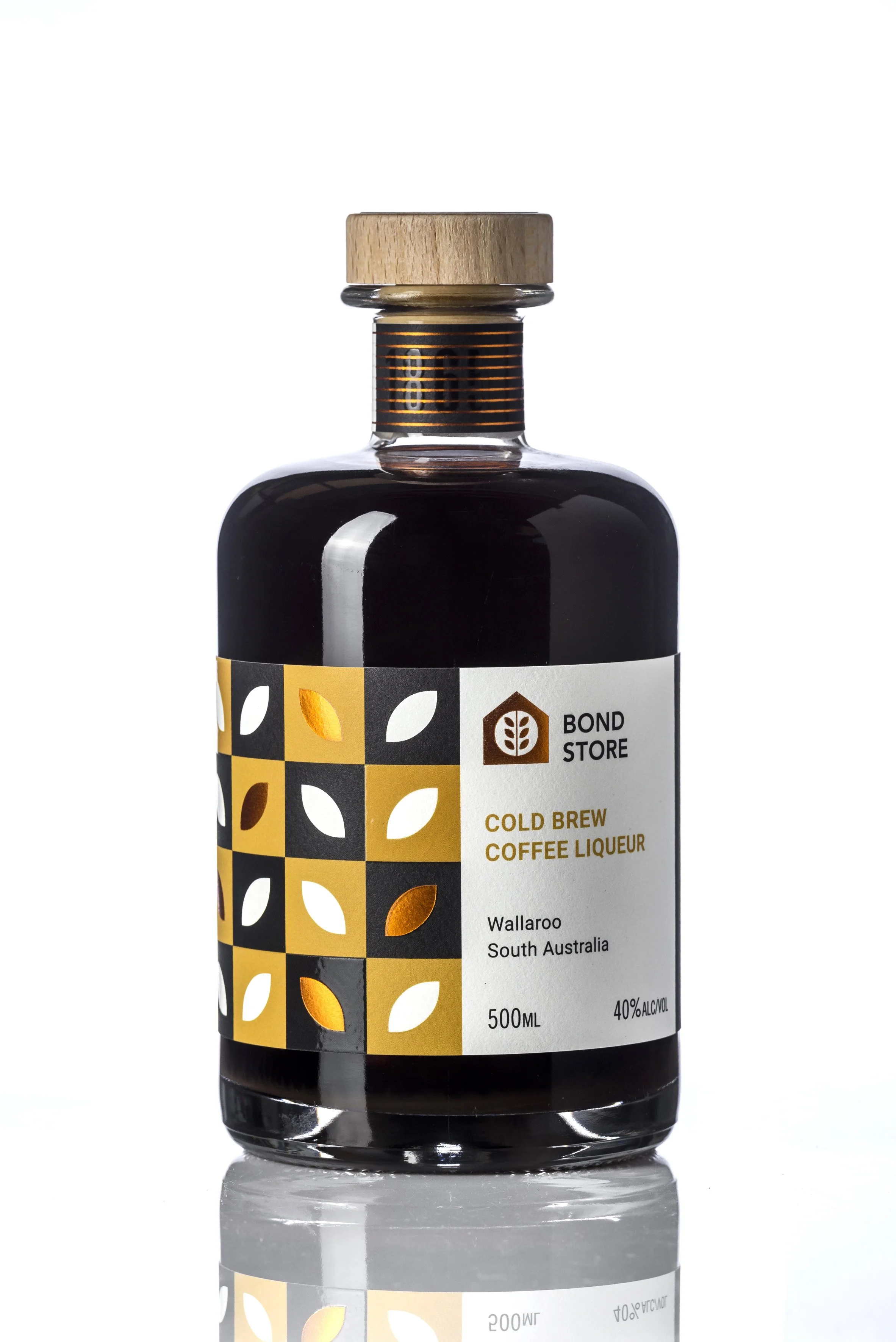 A bottle of Bond Store Cold Brew Coffee Liqueur from Wallaroo, South Australia, with a label showing a yellow and black geometric leaf pattern, a white background, and black text describing the product's alcohol content.