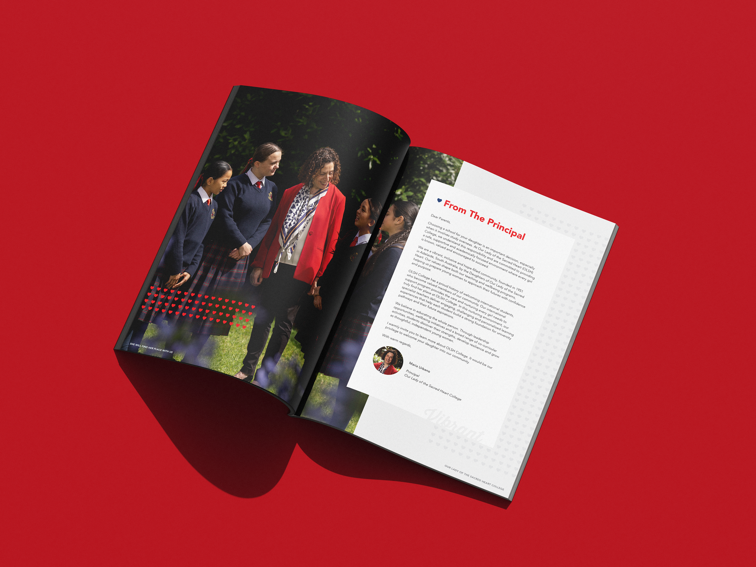 Open magazine featuring a photograph of a woman in a red blazer and curly hair talking to three young girls in school uniforms outdoors, on a red background.