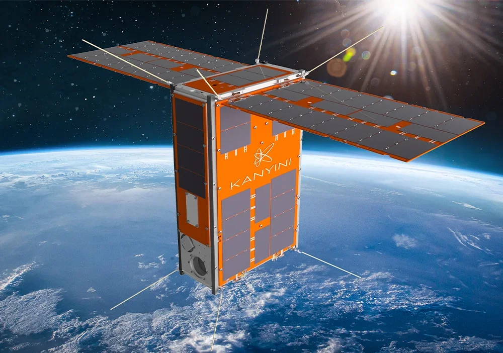 A satellite orbiting above Earth with solar panels and the word "KANYIN" on its body, illuminated by sunlight.