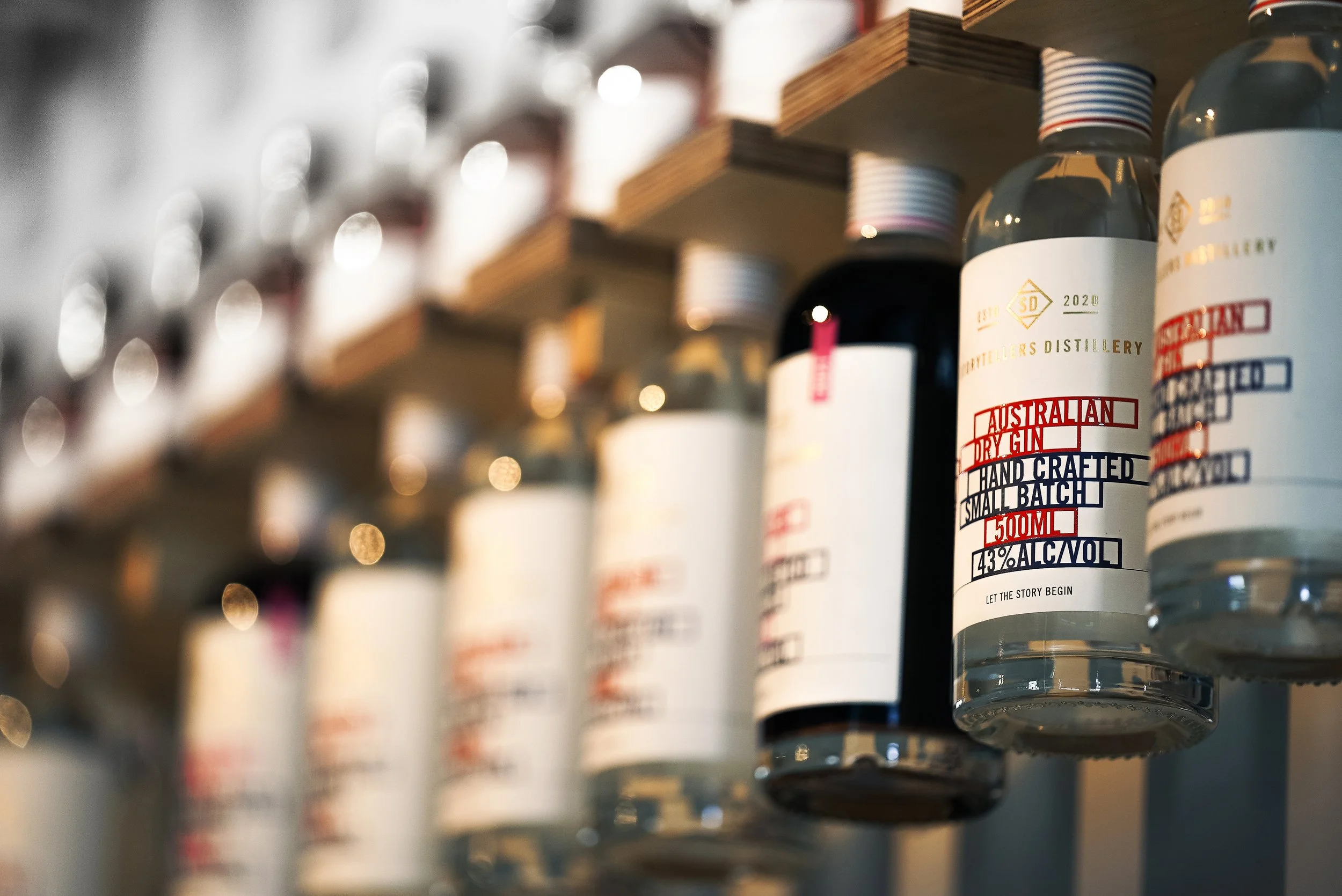 Bottles of Australian dry gin on a shelf, with blurred background of more bottles and shelves.