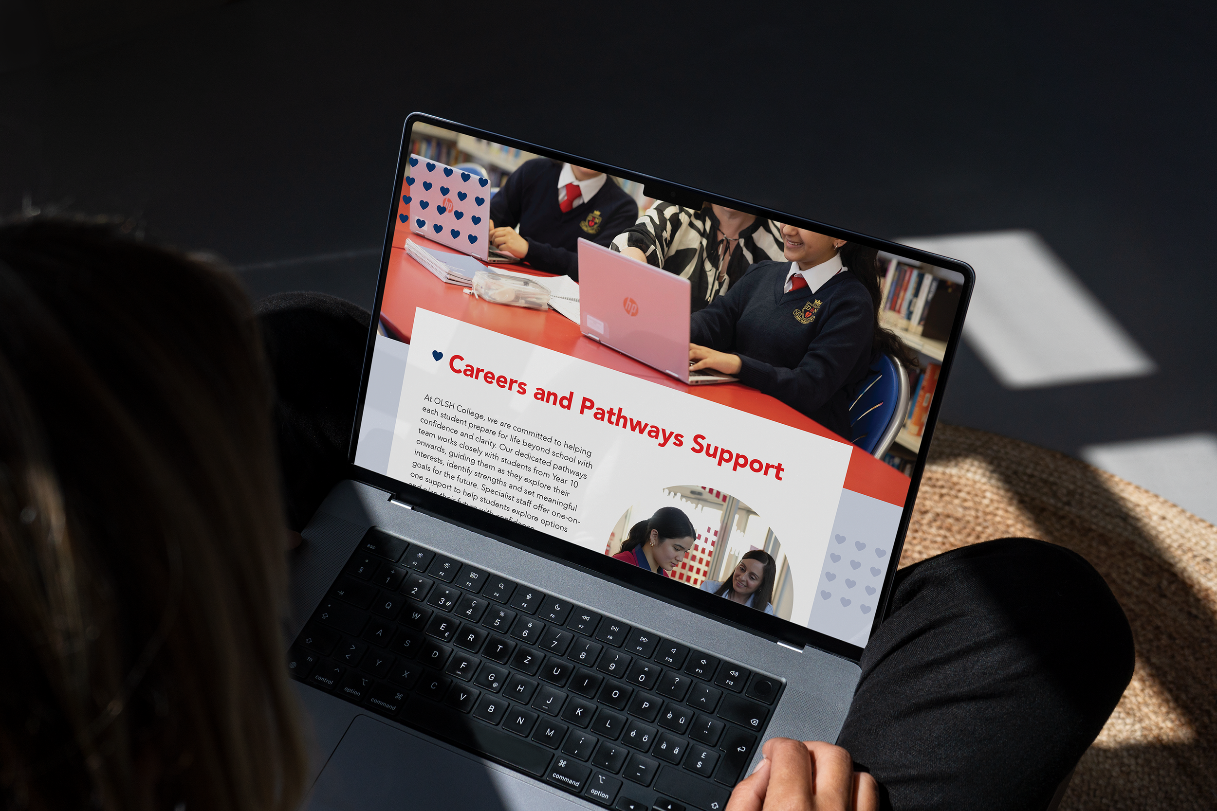 Person holding a laptop displaying a webpage titled 'Careers and Pathways Support' with students in a classroom setting on the screen.