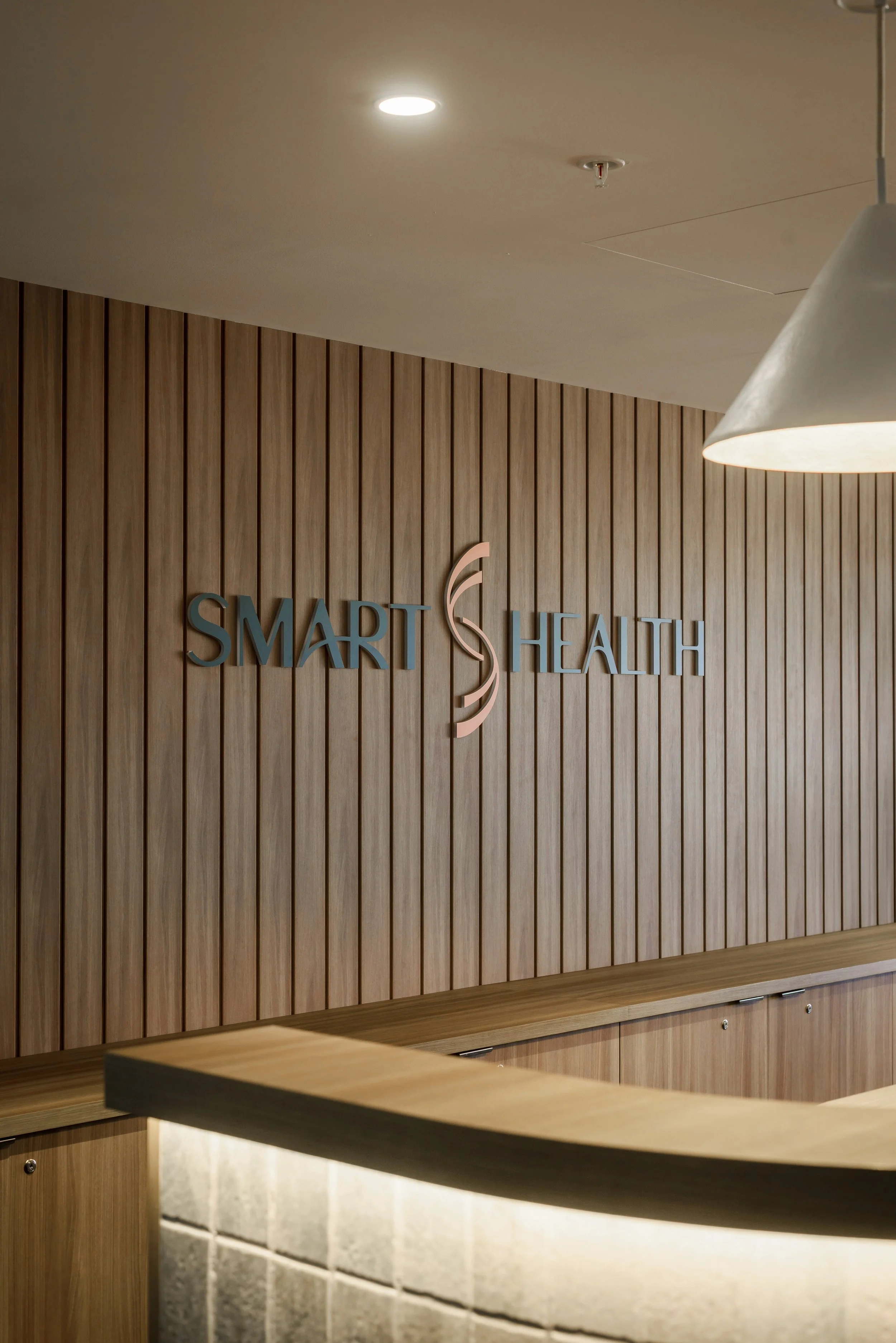 Reception desk with a wooden wall background and sign that reads 'Smart Health' with a stylized logo.