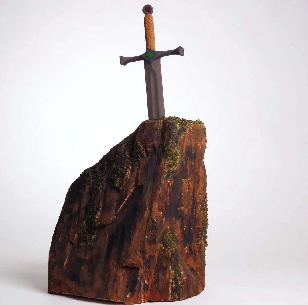 Une sculpture de bois représentant une épée enfoncée dans une roche.