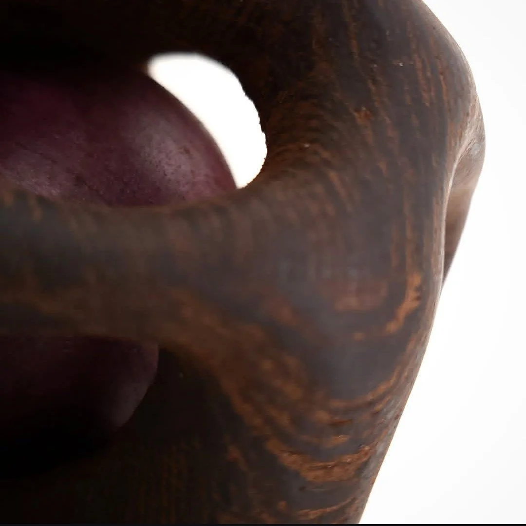 Vue oblique d'une sculpture en bois avec un trou circulaire au centre.