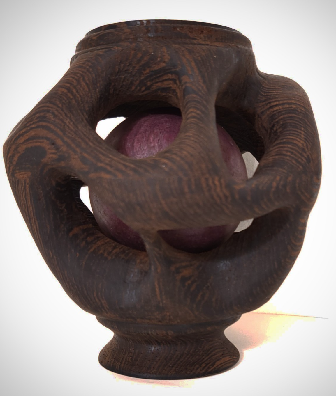 Une sculpture en bois avec une forme circulaire contenant une boule violette au centre.
