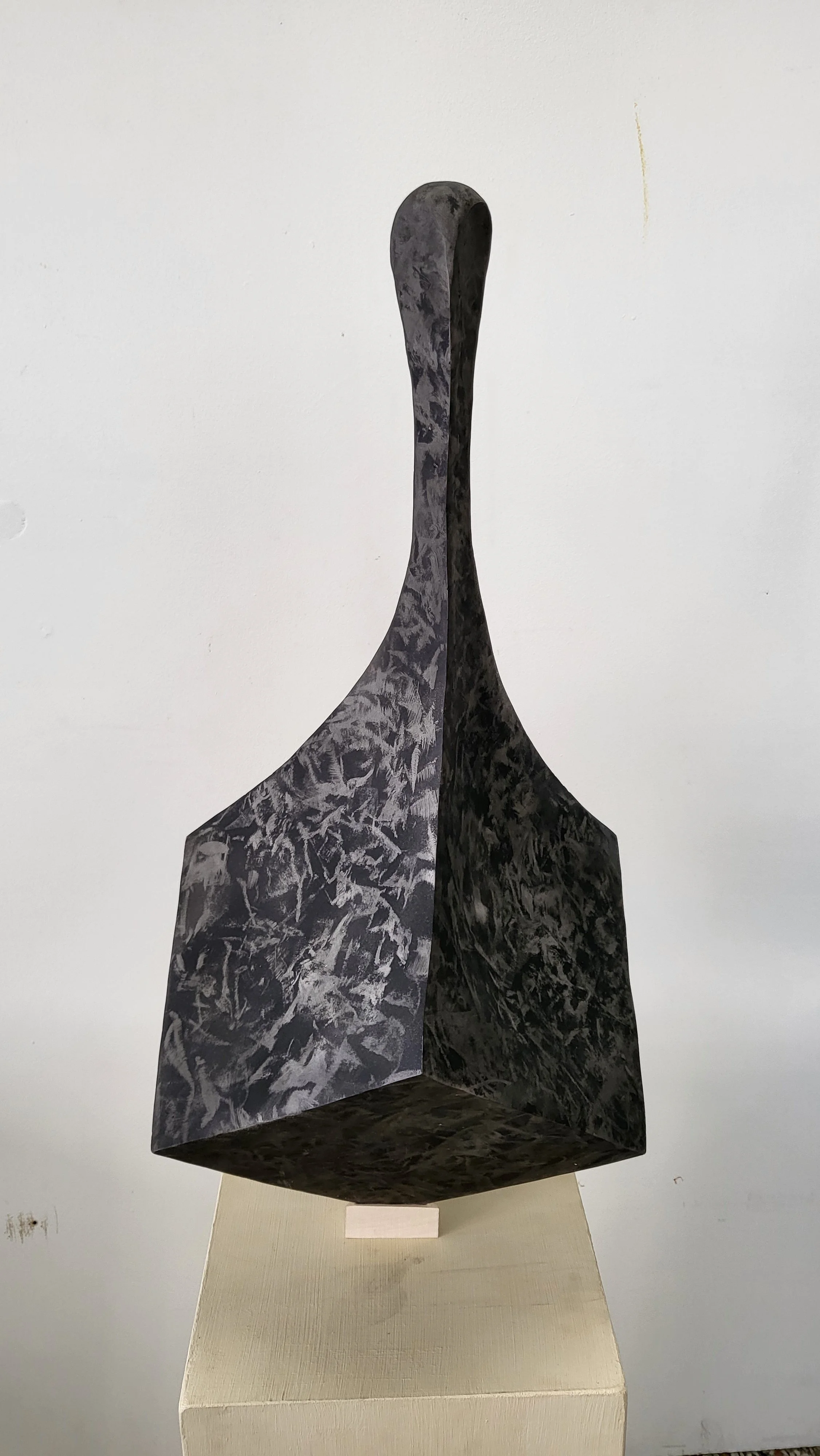 Sculpture moderne en forme de figure abstraite en noir et blanc, exposée sur un socle blanc.
