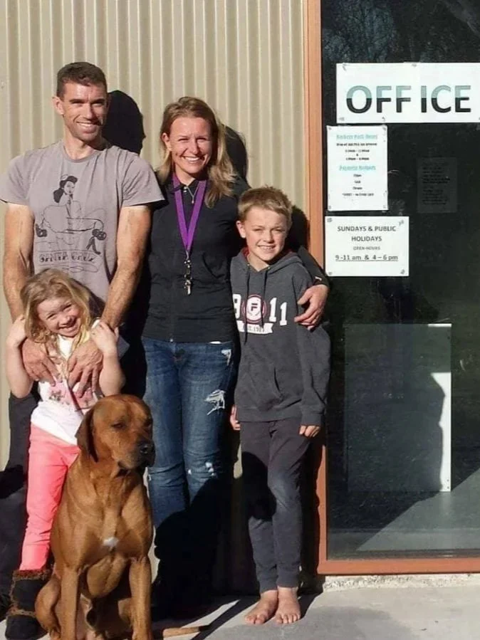 A family of four with a dog standing outside the entrance to an office building.