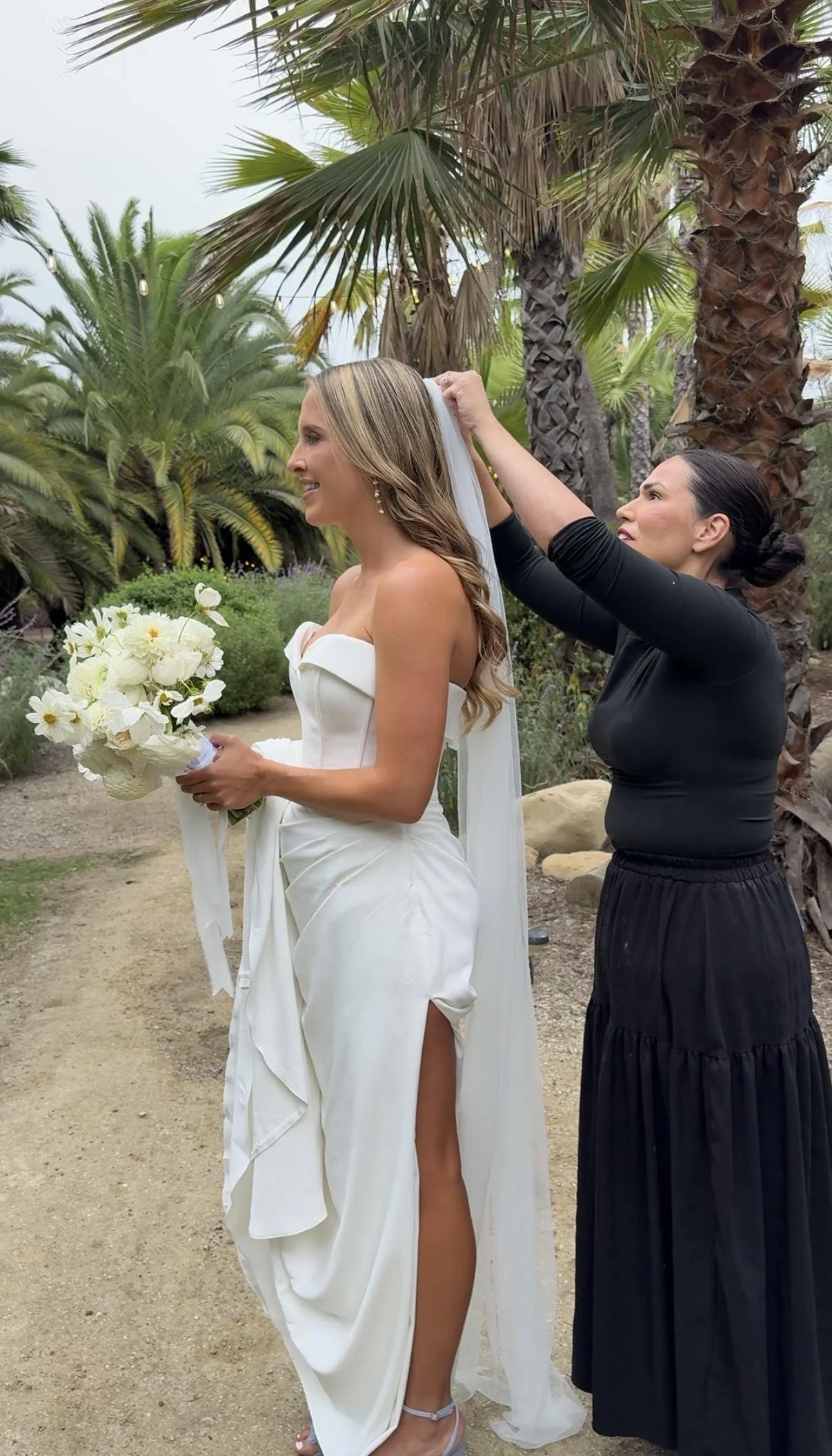 Bridal hairstylist adjusting bride's hair during wedding day touch-ups in Ojai.