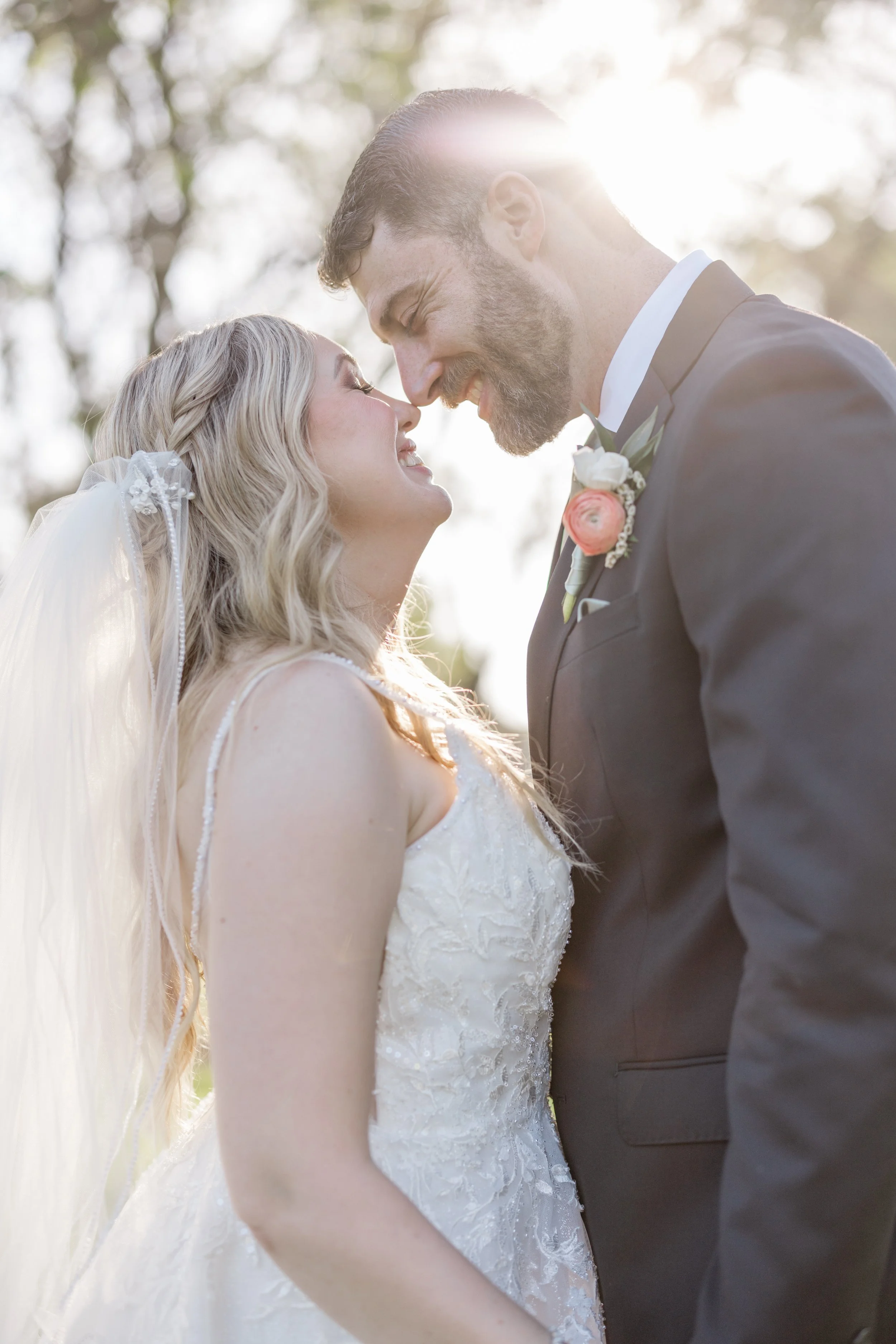 Close-up of a blonde bride with a braided half-up hairstyle and soft glam makeup smiling at the groom at Los Robles Greens Thousand Oaks.