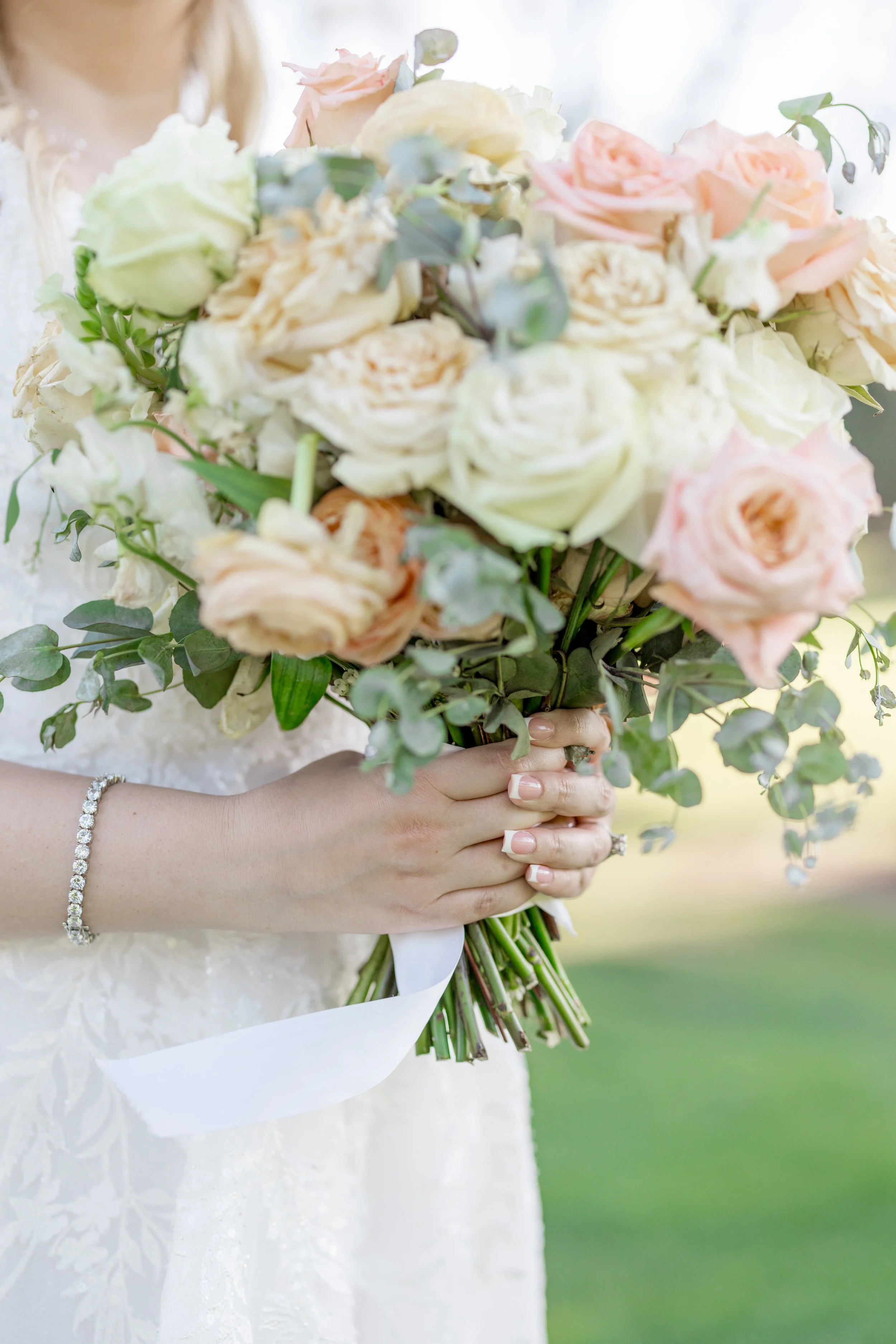 Close-up of bridal bouquet with blush and ivory roses and soft greenery.
