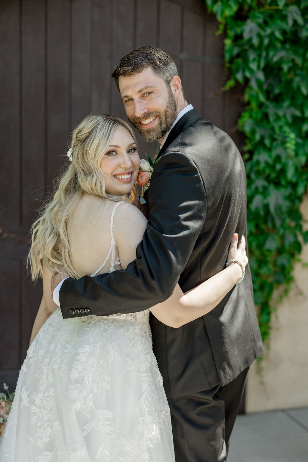 Bride with soft glam makeup and log eaves embracing groom at Los Robles Greens in Thousand Oaks, CA