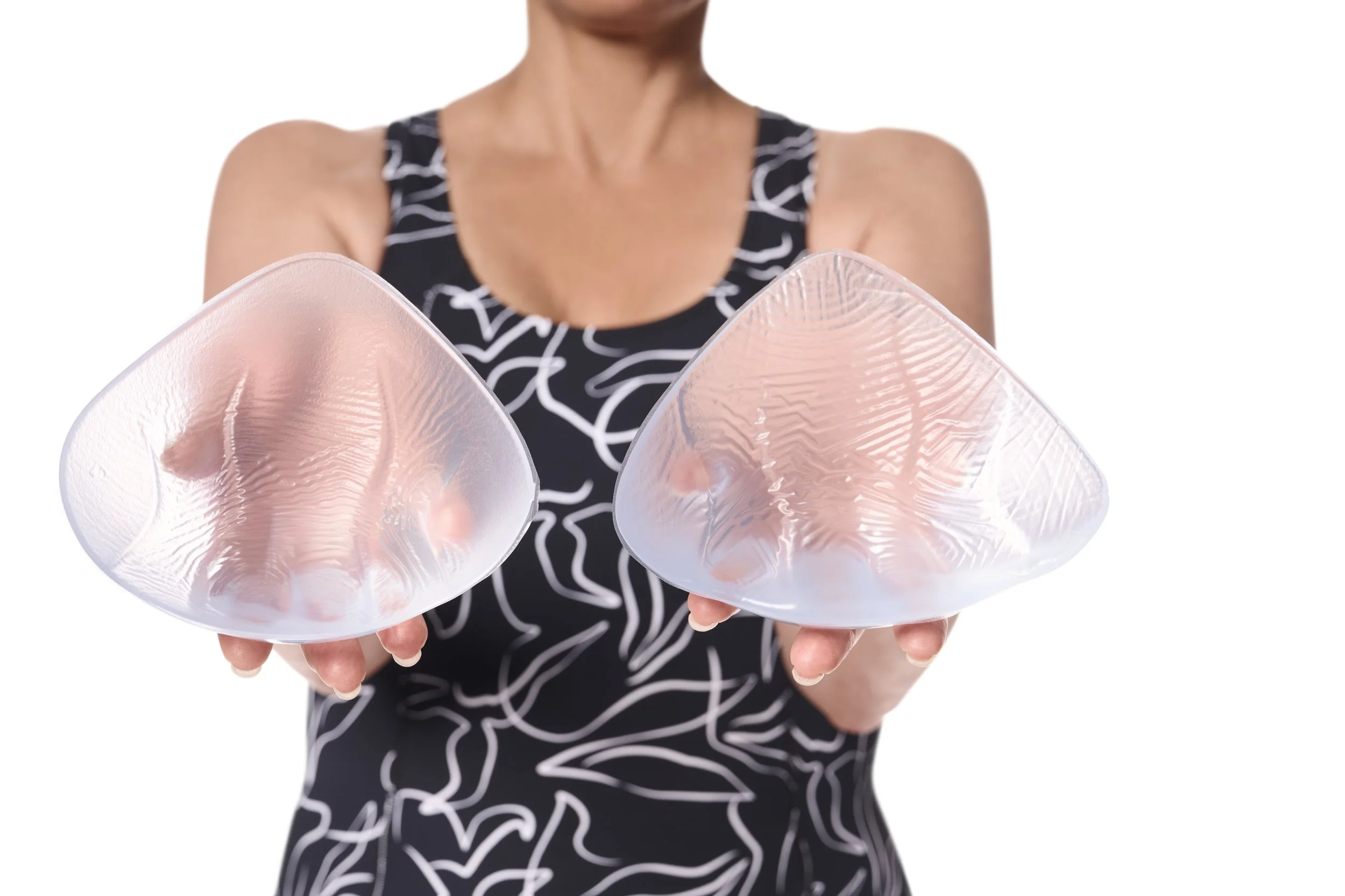 A woman wearing a black and white patterned sleeveless dress holding two large seashells.