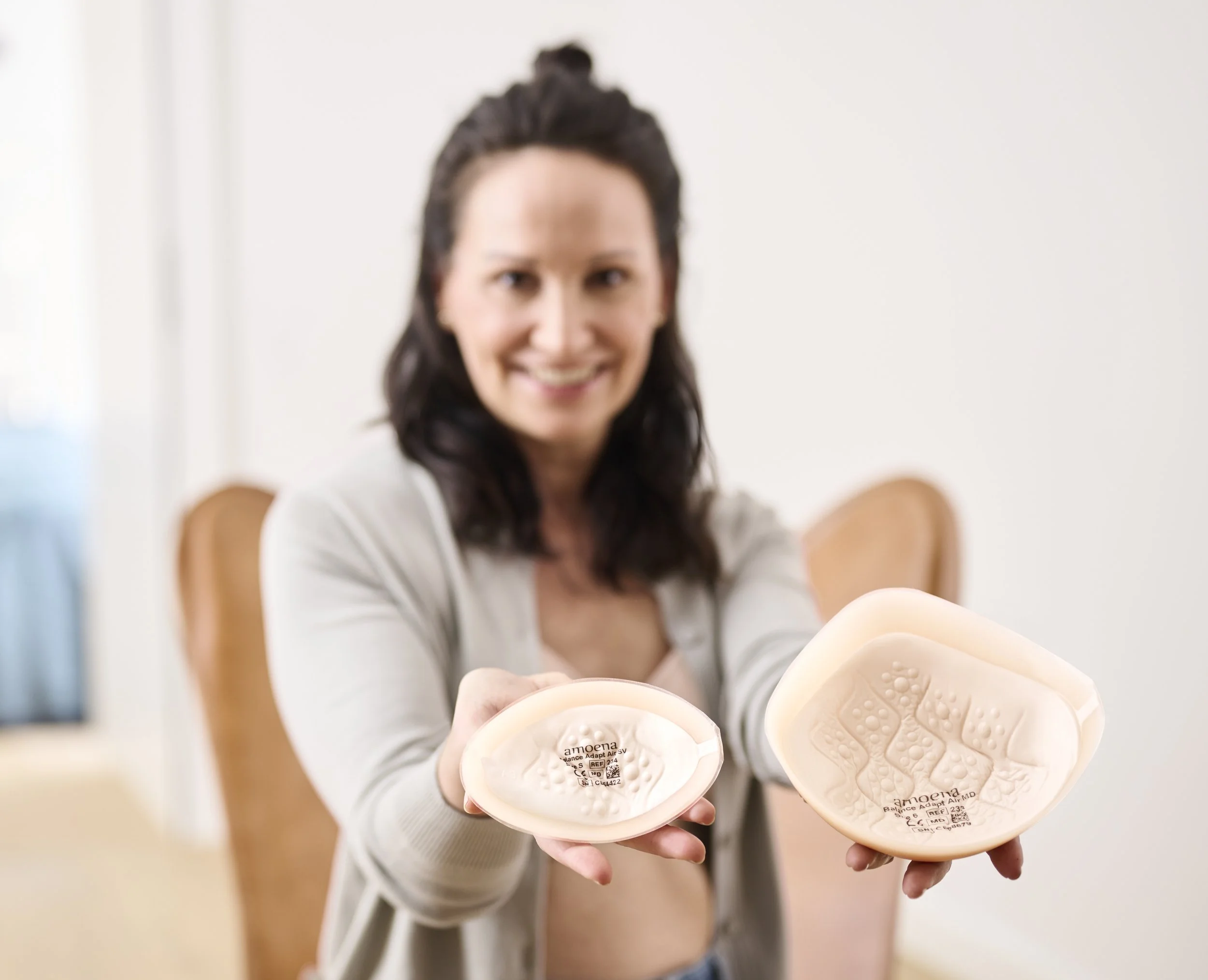 A woman holding two silicone breast implants, showing the internal structure of the implants.