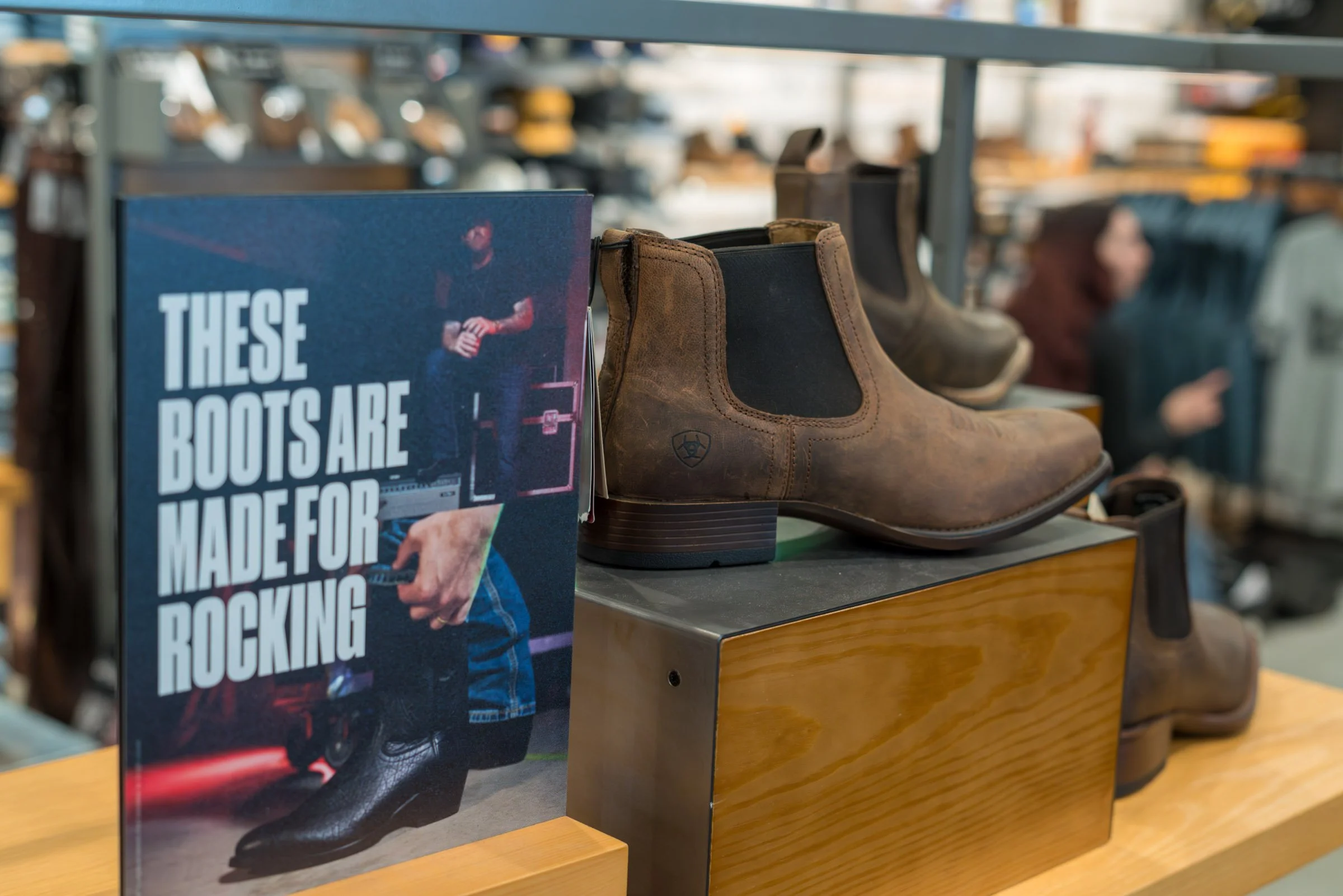 A display of cowboy boots and a magazine titled 'These Boots Are Made for Rocking' in a store.