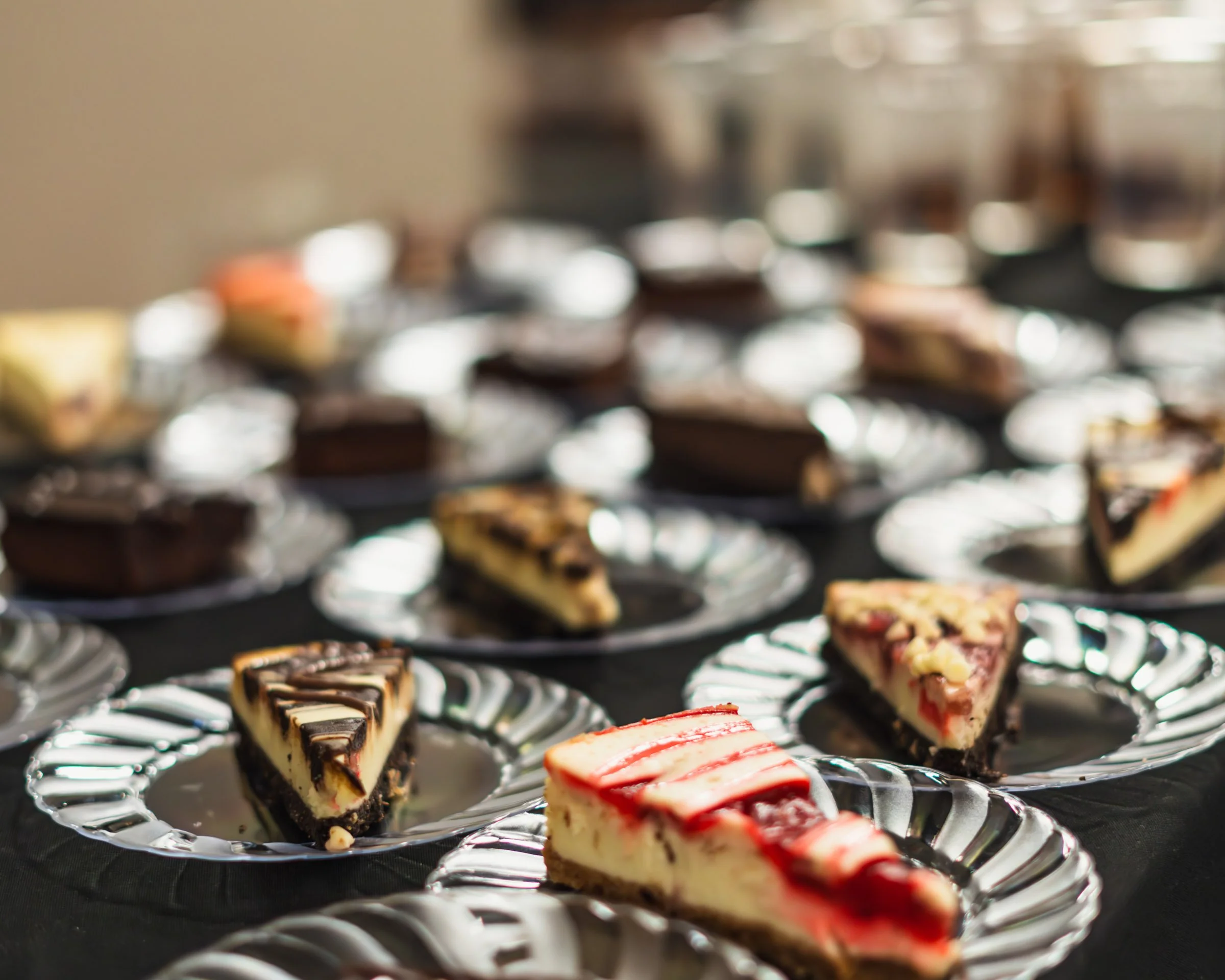 Assorted mini cheesecakes with different toppings on a silver platter.