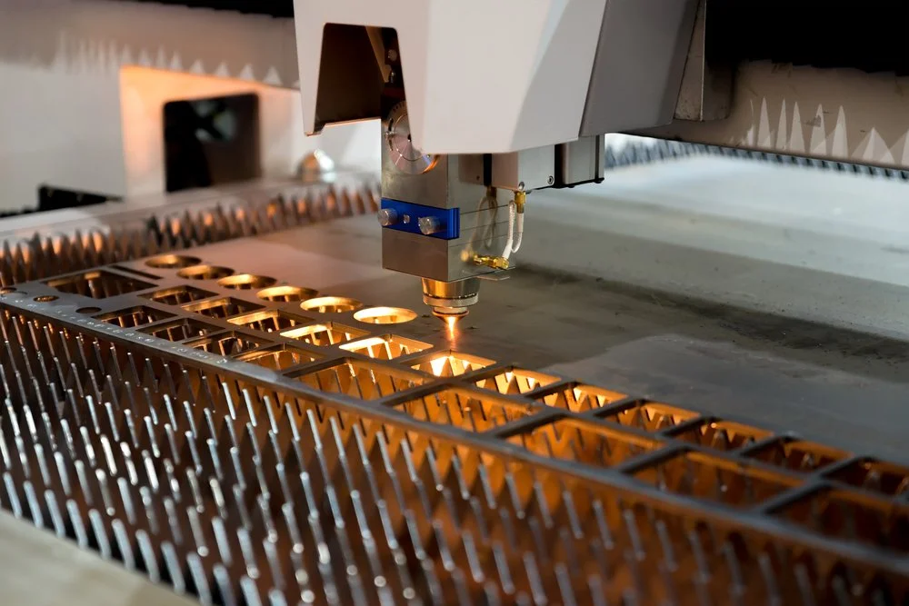 A high-speed industrial 6kW flatbed fiber laser head piercing a piece of heavy gauge steel sheet.