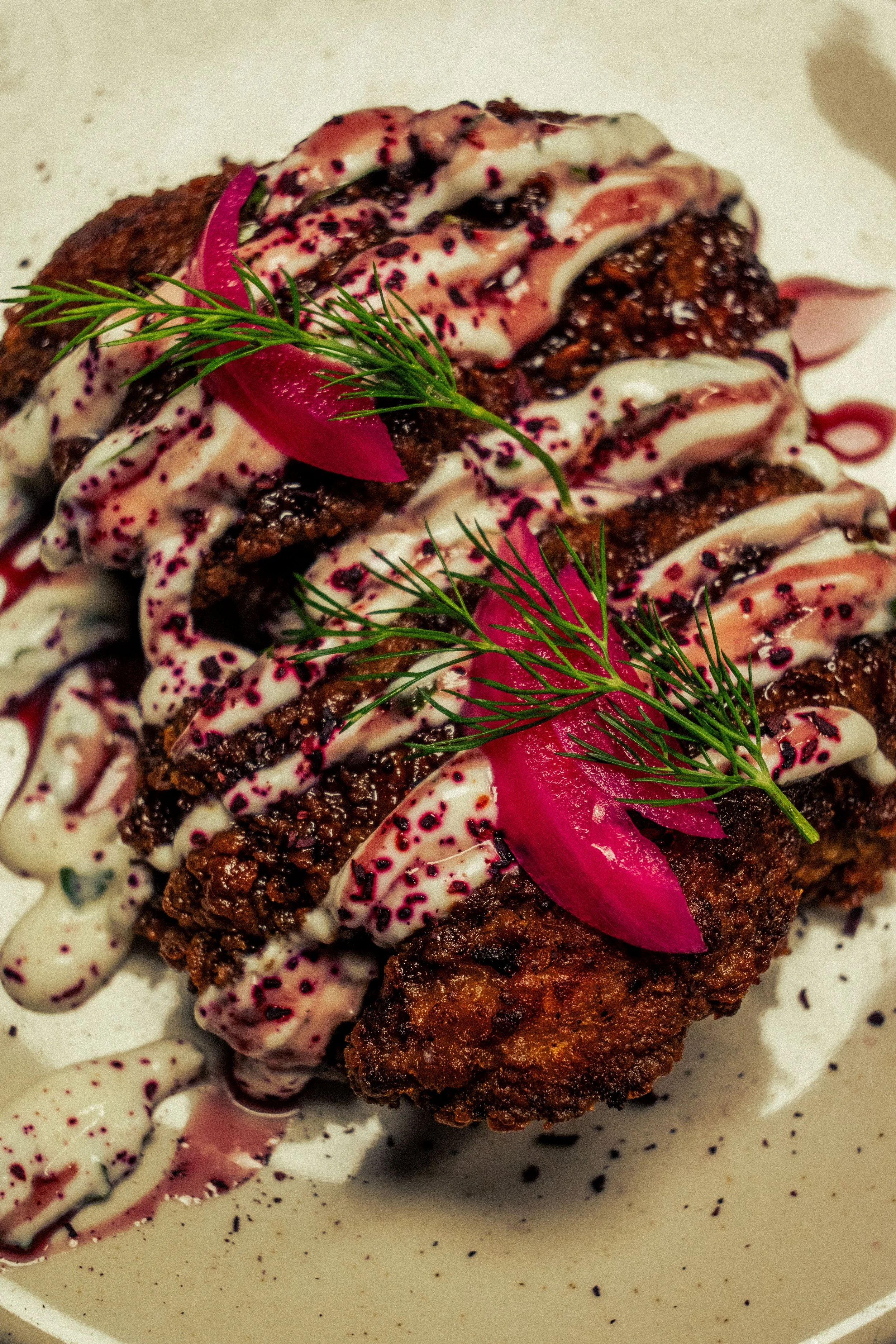 Plat de poulet frit avec sauce blanche, garnitures de radis roses, herbes fraîches et sauce violette.