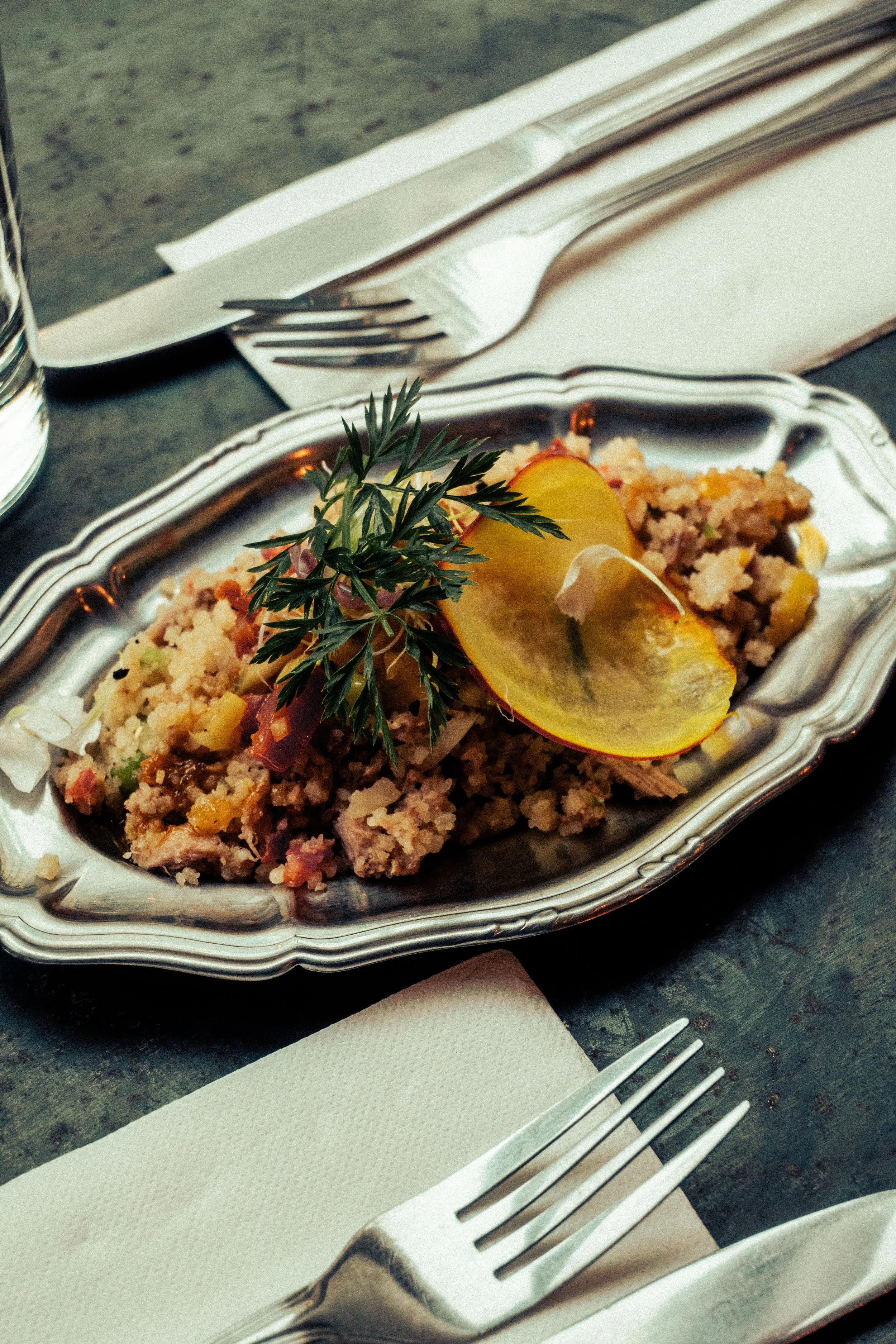 Salade d'attiéké au thon - comme un garba ivoirien- garnie de citron, herbes et pickles, présentée dans un plat en argent