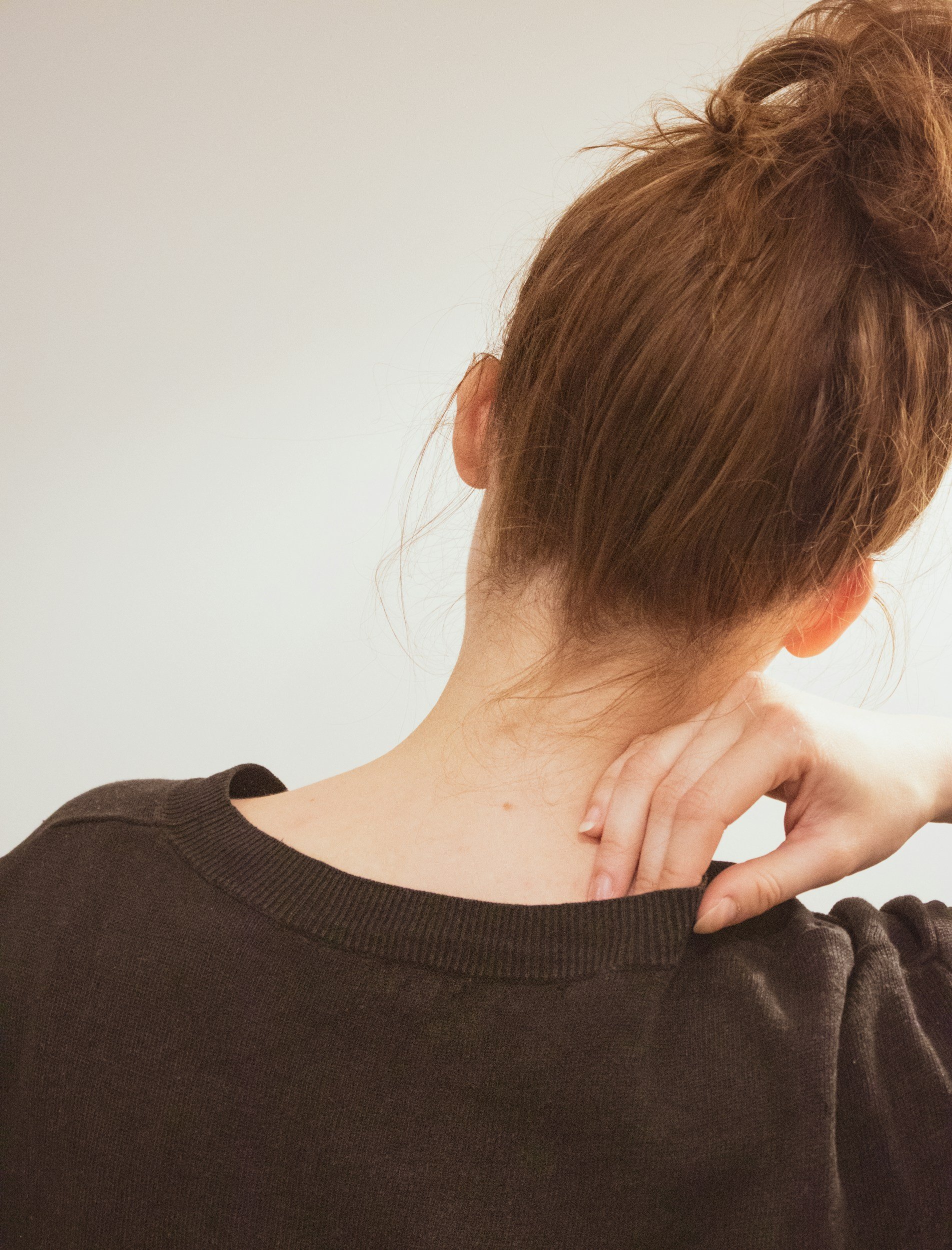 Woman holding tension in her neck and shoulders from chronic stress